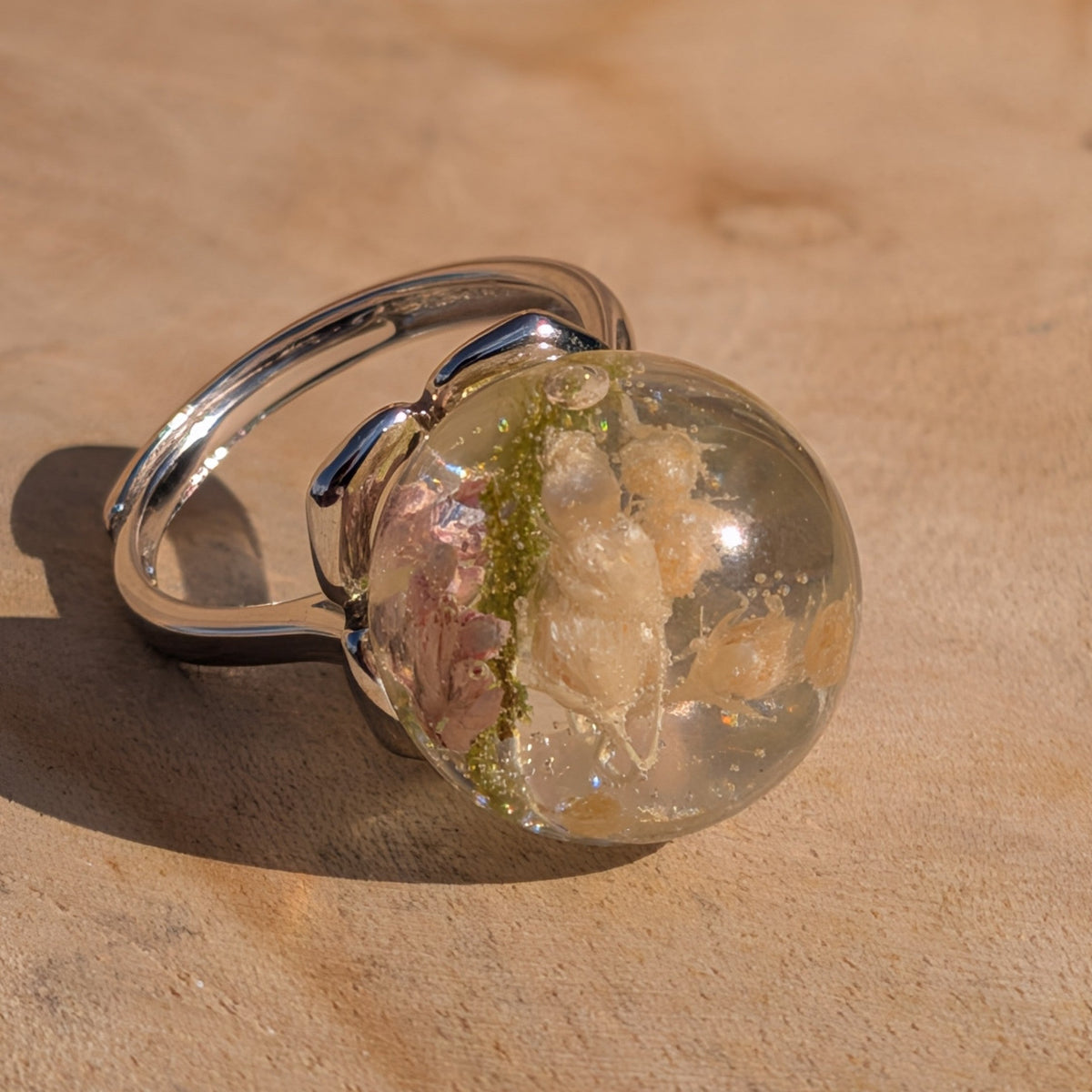 Close-up of clear resin sphere ring showing wild flowers and green moss – EL-Creations