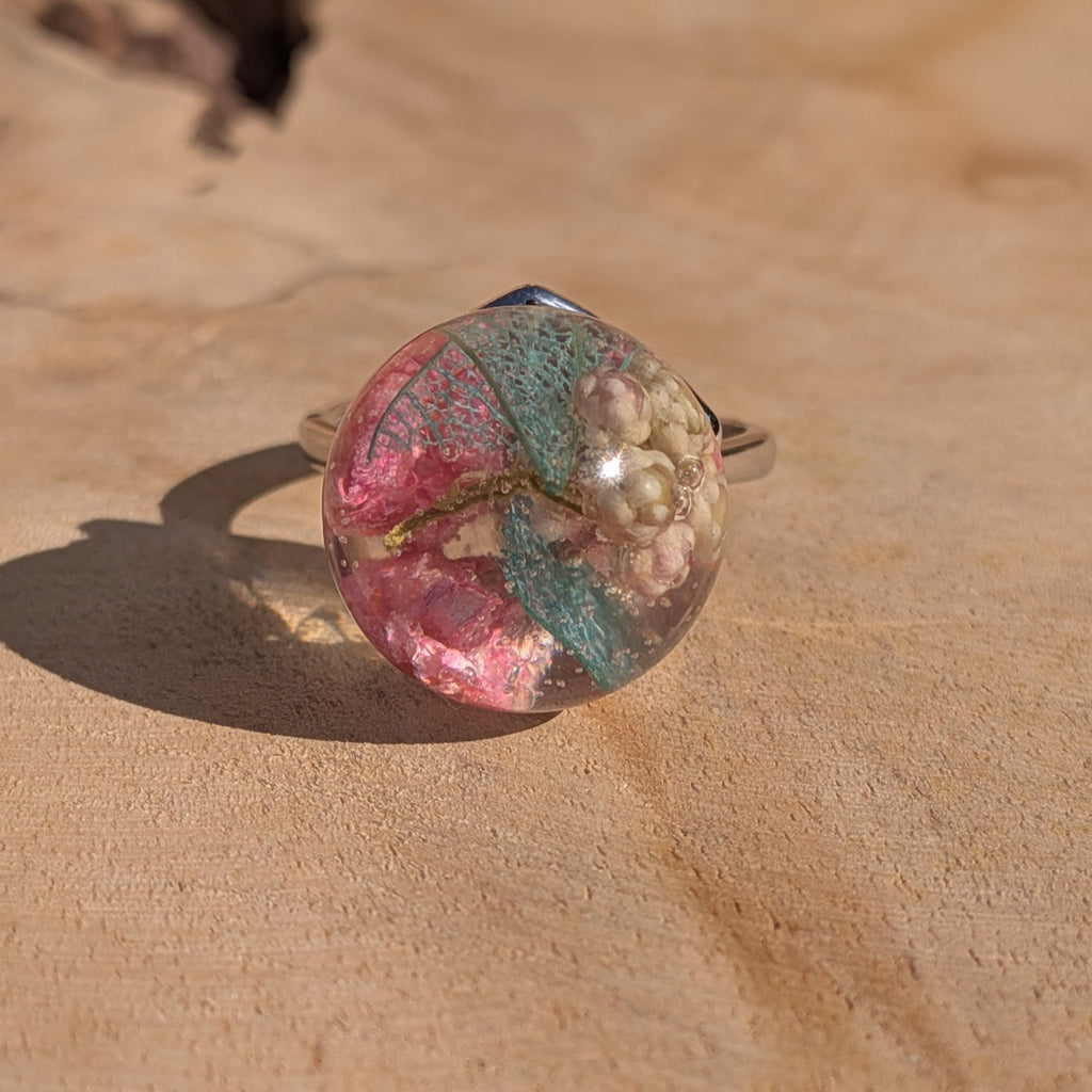 Clear resin ball ring with pressed flowers held between fingers – botanical jewelry by EL-Creations