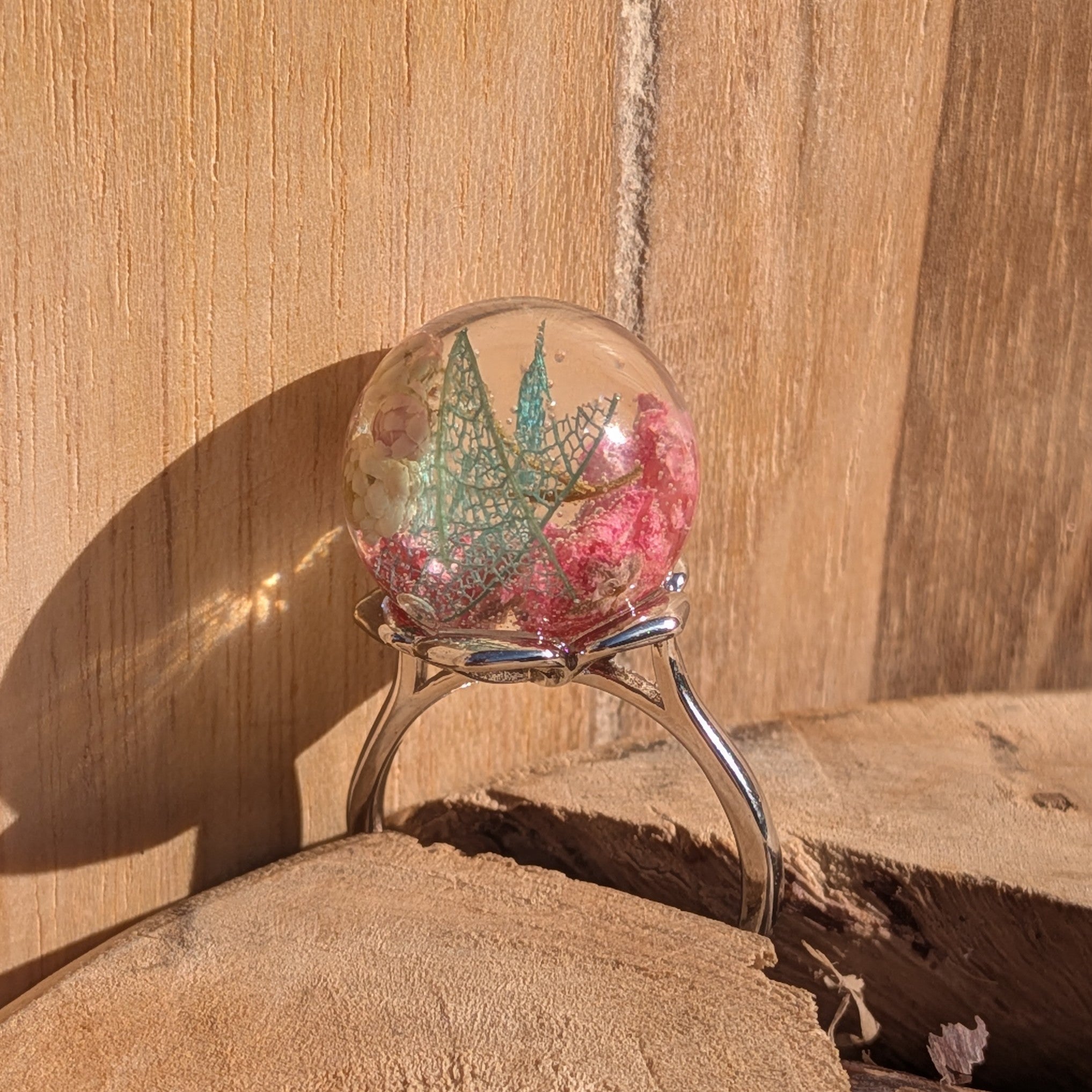 Globe resin ring with real pressed wildflowers and skeleton leaf – top view on wooden background – EL-Creations