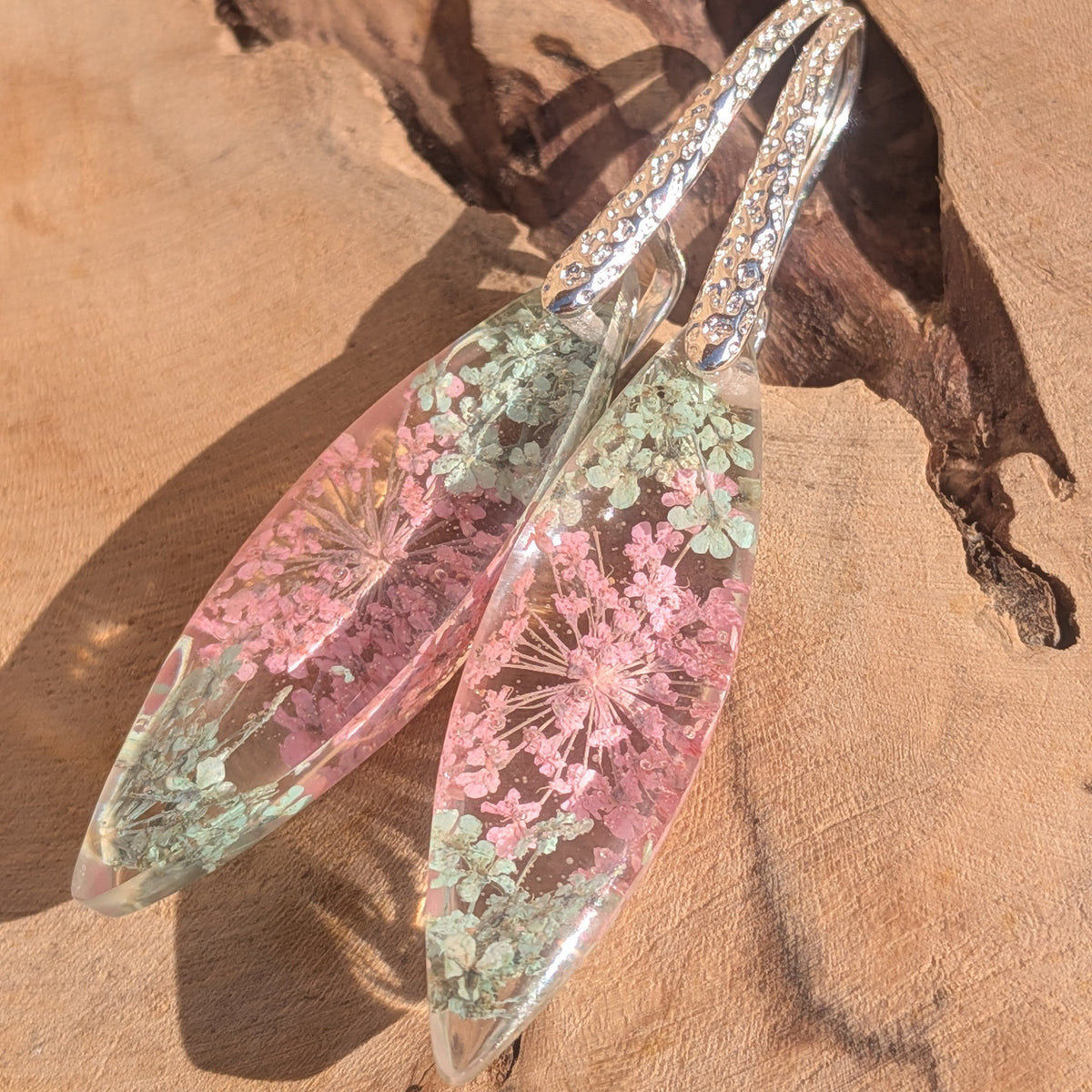 Pair of clear resin leaf-shaped earrings with pink Queen Anne's lace on wooden background – EL-Creations