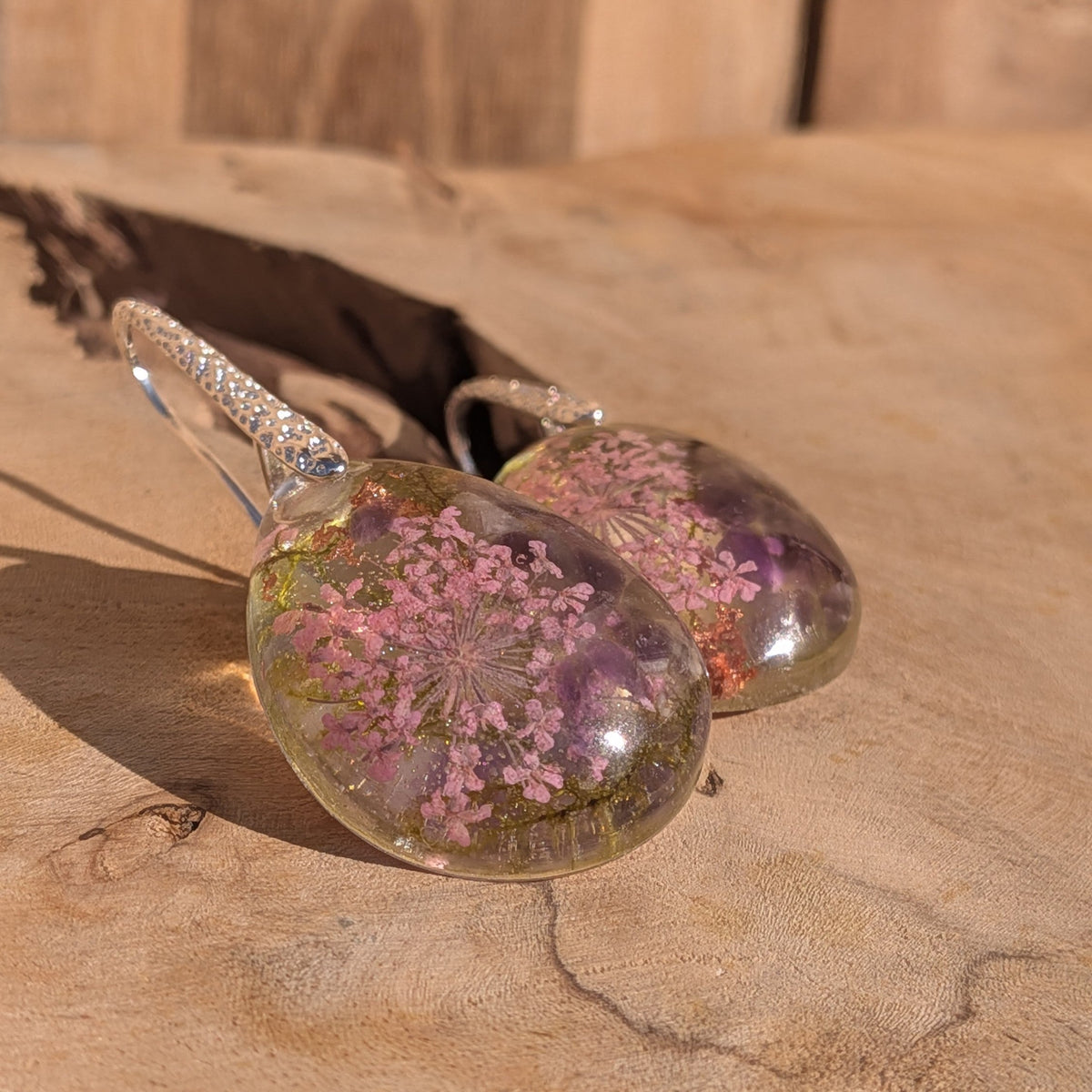 Close-up of pink Queen Anne’s lace and amethyst preserved in clear resin drop – EL-Creations