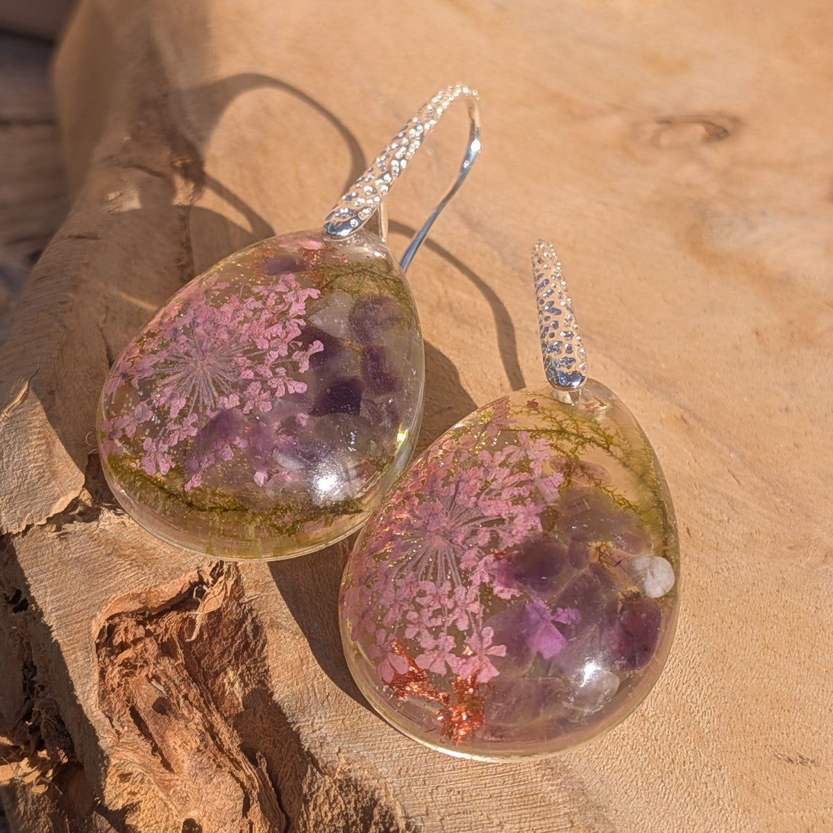 Nature-inspired resin drop earrings with pink pressed flowers and amethyst chips in sunlight – EL-Creations