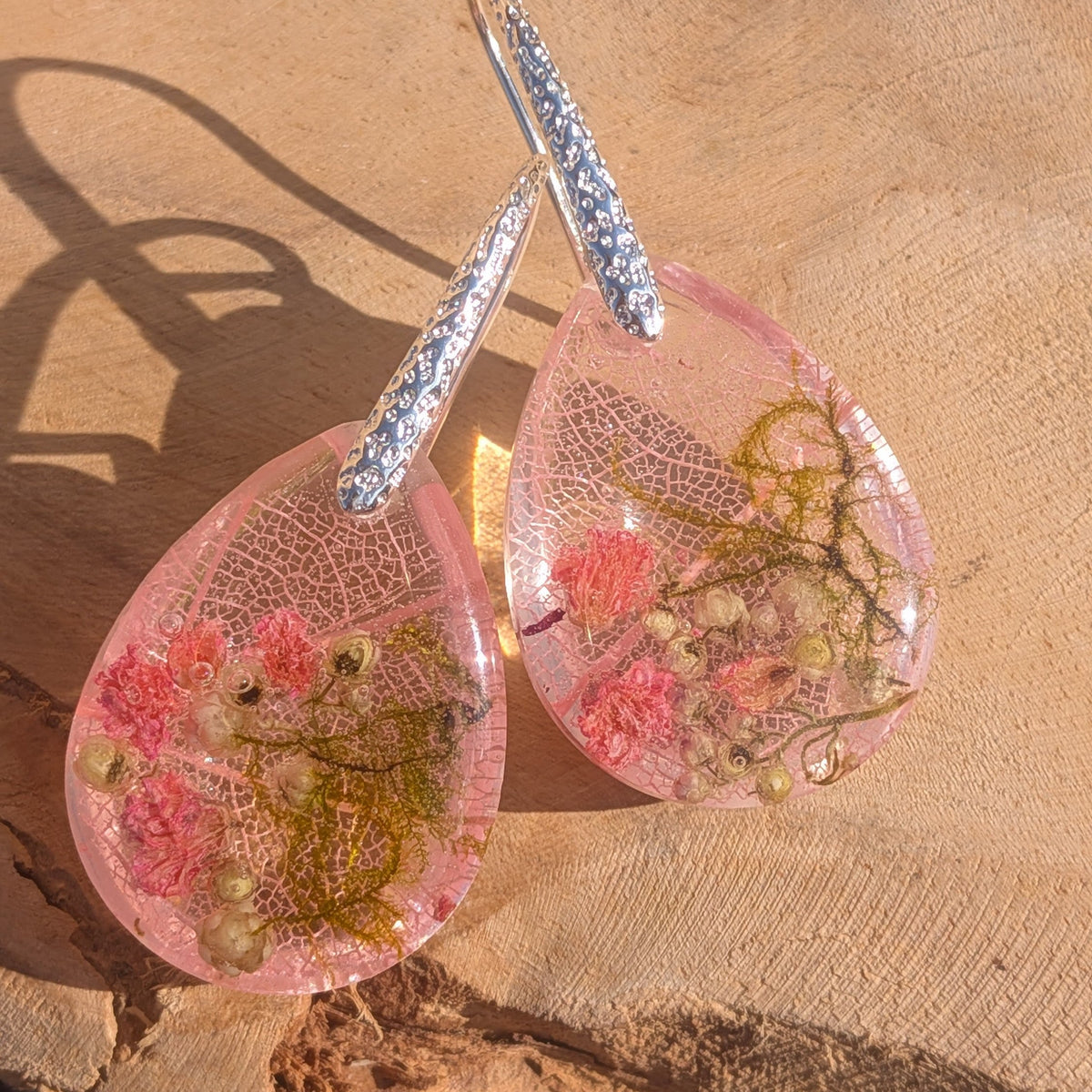 Blush pink resin drop earrings with pressed skeleton leaf on driftwood surface – EL-Creations