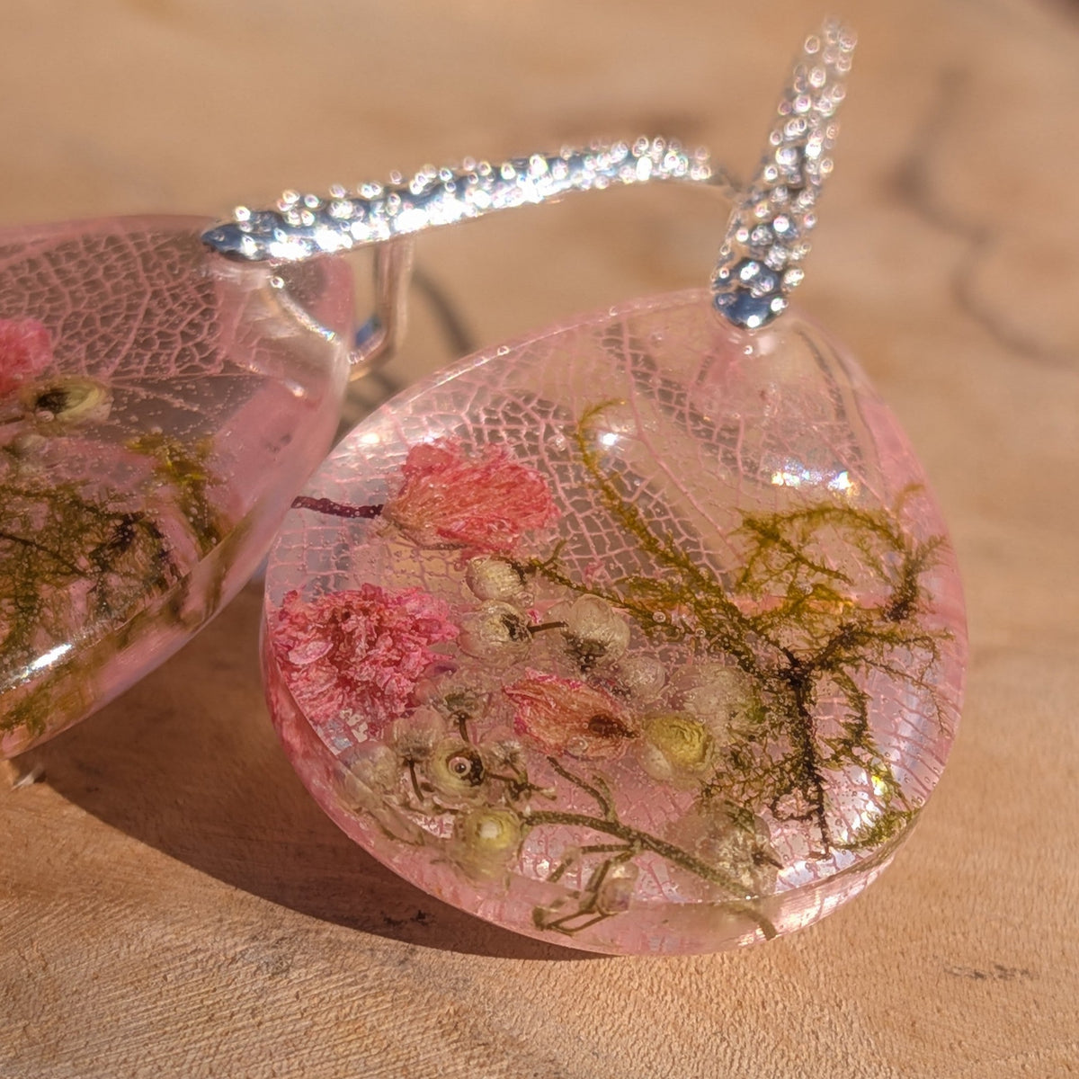 Pair of blush pink resin drop earrings with real dried botanicals on wooden background – EL-Creations