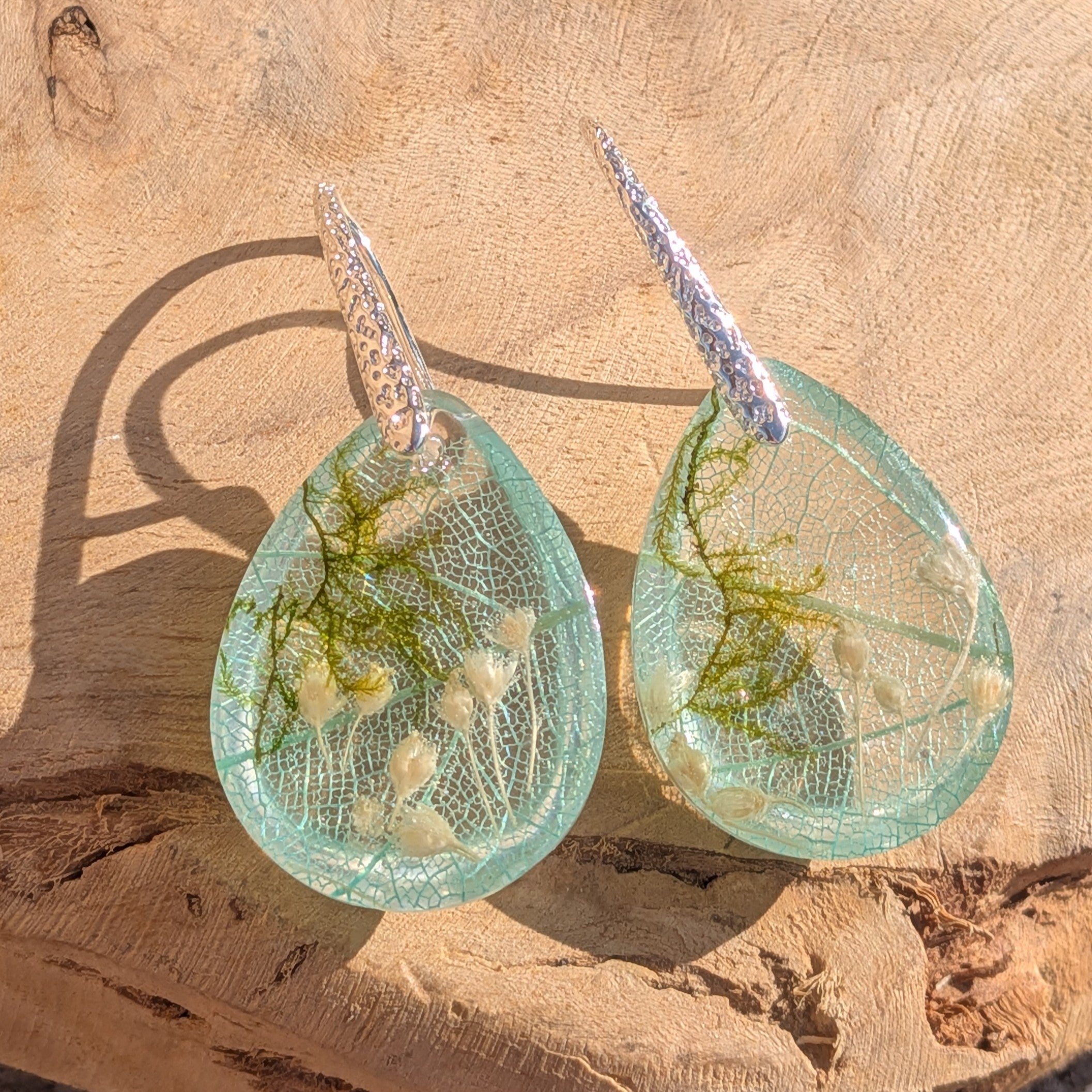 Skeleton leaf resin earrings side profile on wood showing dome depth and botanical inclusions – EL-Creations