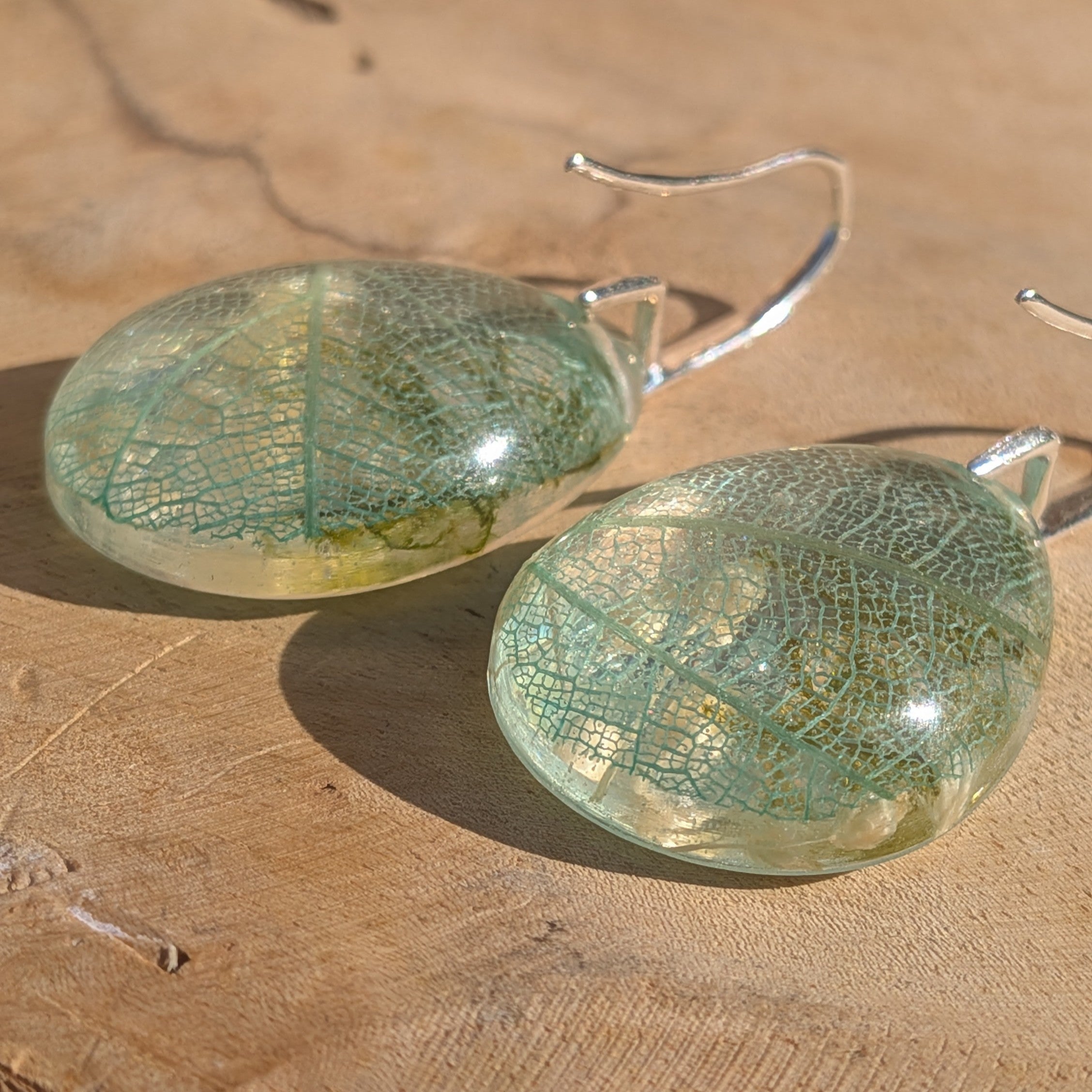Skeleton leaf resin teardrop earrings pair on wood back view showing silver hooks and resin dome – EL-Creations
