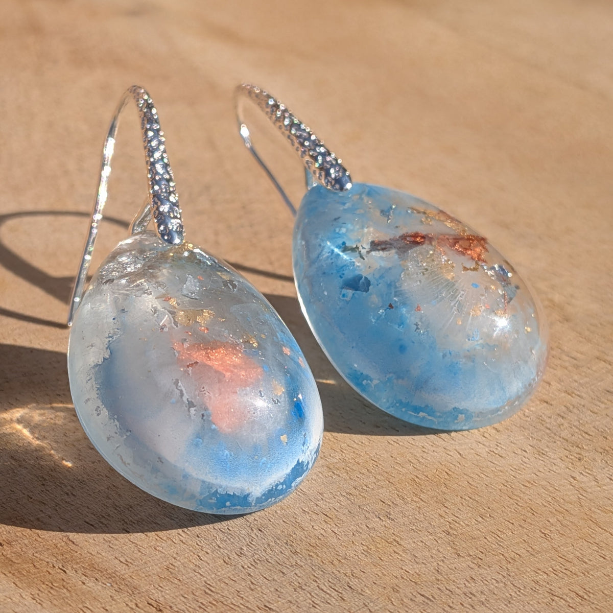 Front view of blue and white resin drop earrings with copper flakes and silver hooks, EL-Creations