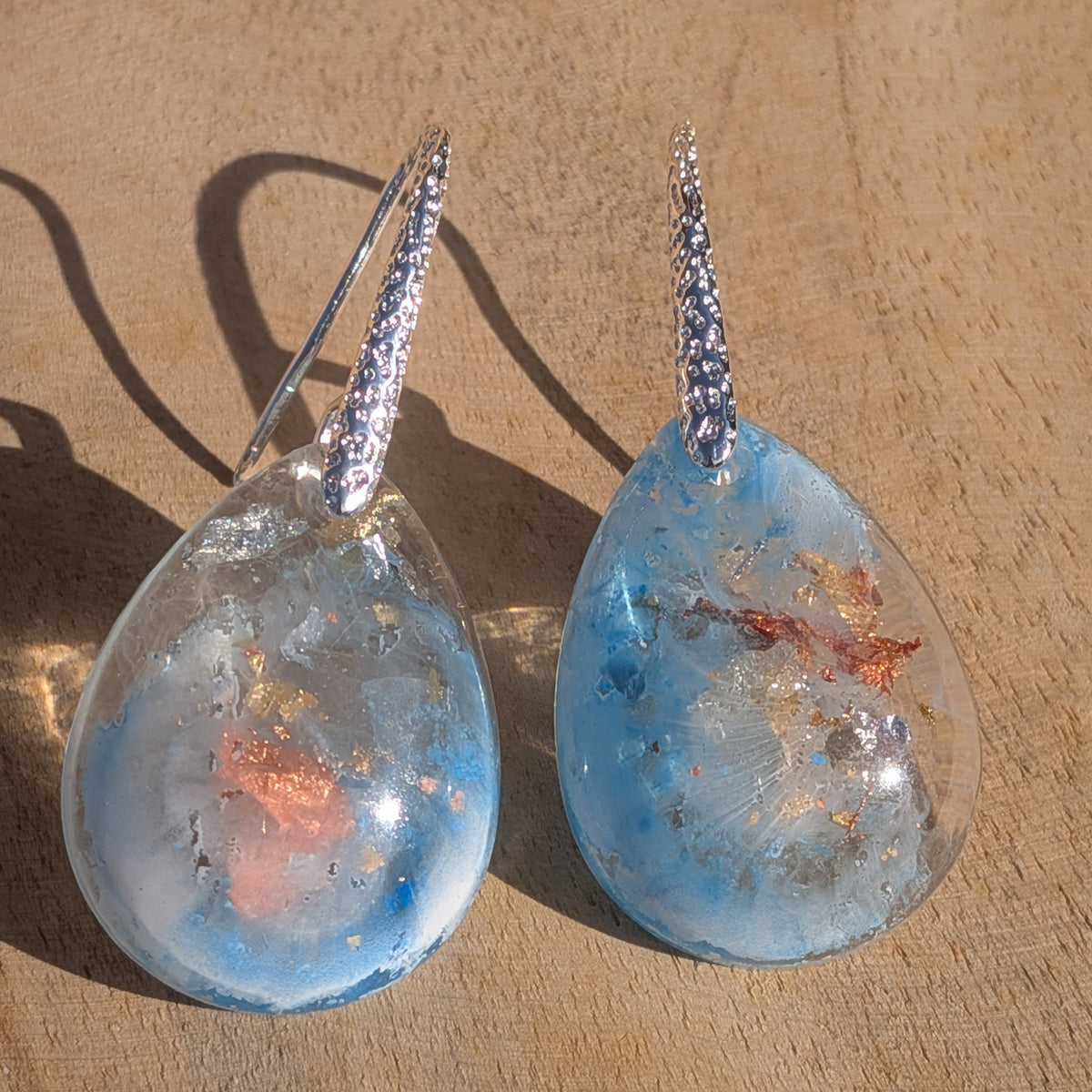 Blue and white resin drop earring worn on the ear showing copper details, EL-Creations