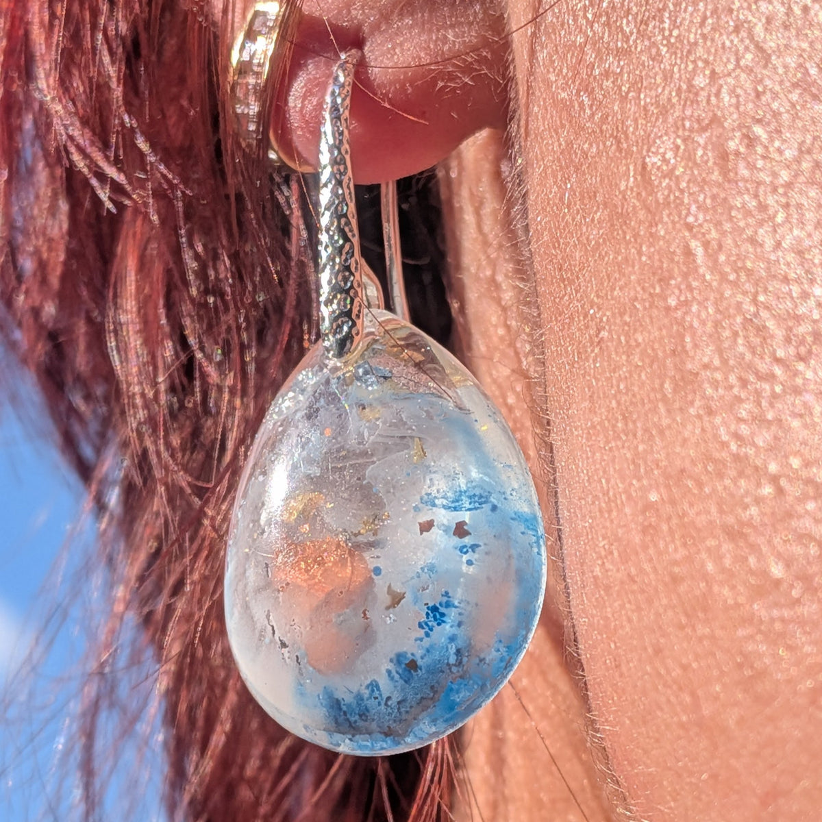 Side view of blue and white resin earrings showing glossy rounded drops, EL-Creations