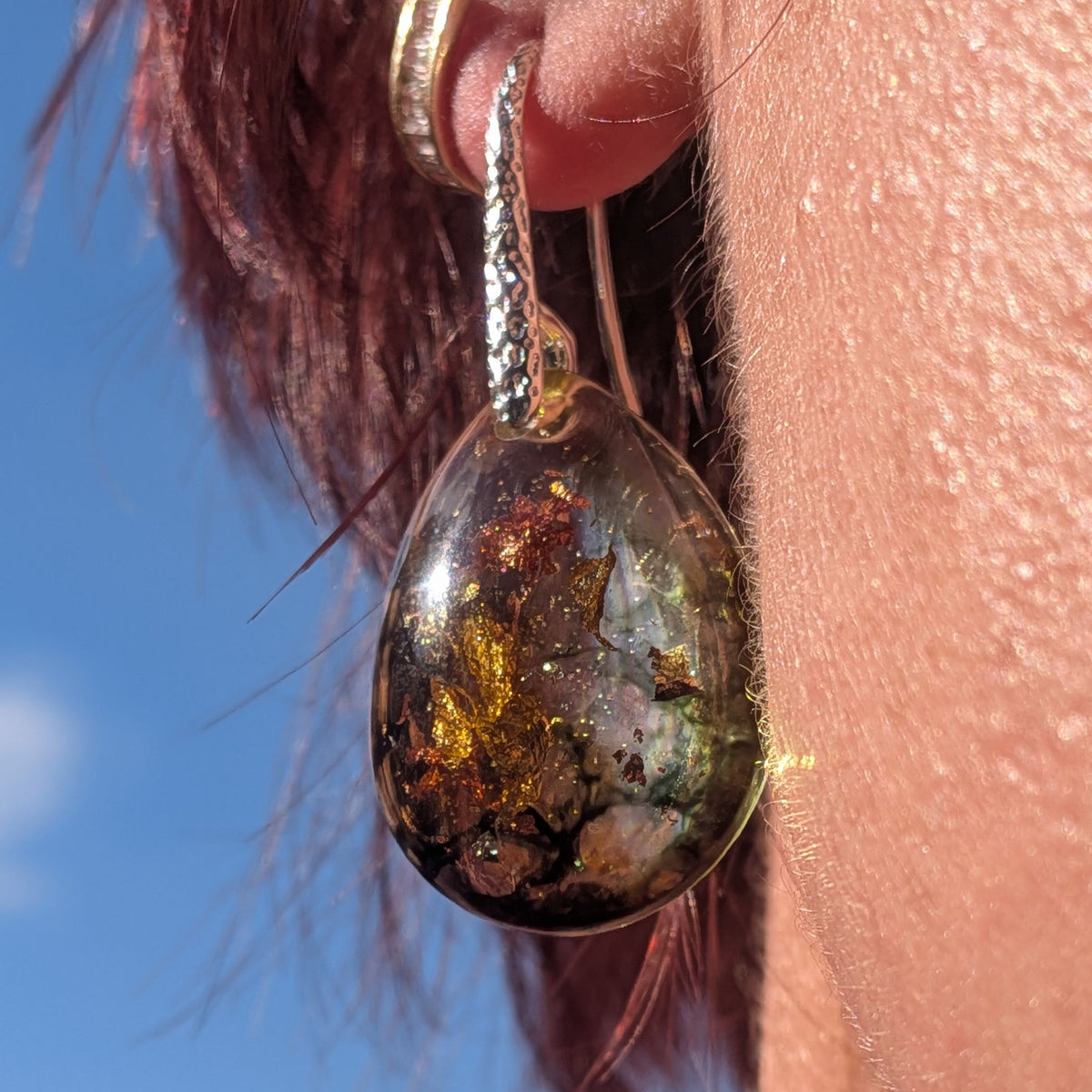Olive green and amber teardrop earring worn on the ear showing its length, EL-Creations