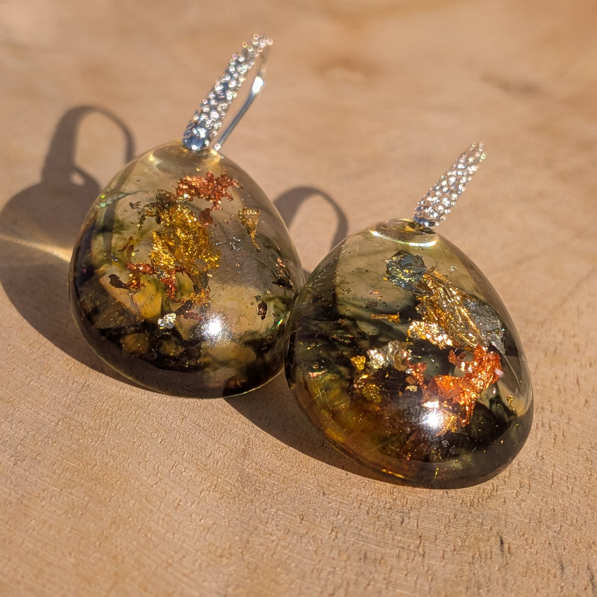Angled view of amber and olive resin earrings with dark abstract patterns, EL-Creations