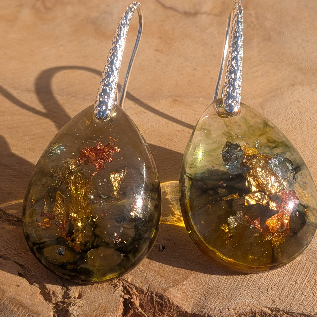 Front close-up of olive and amber resin earrings with dark swirls and metallic flakes, EL-Creations