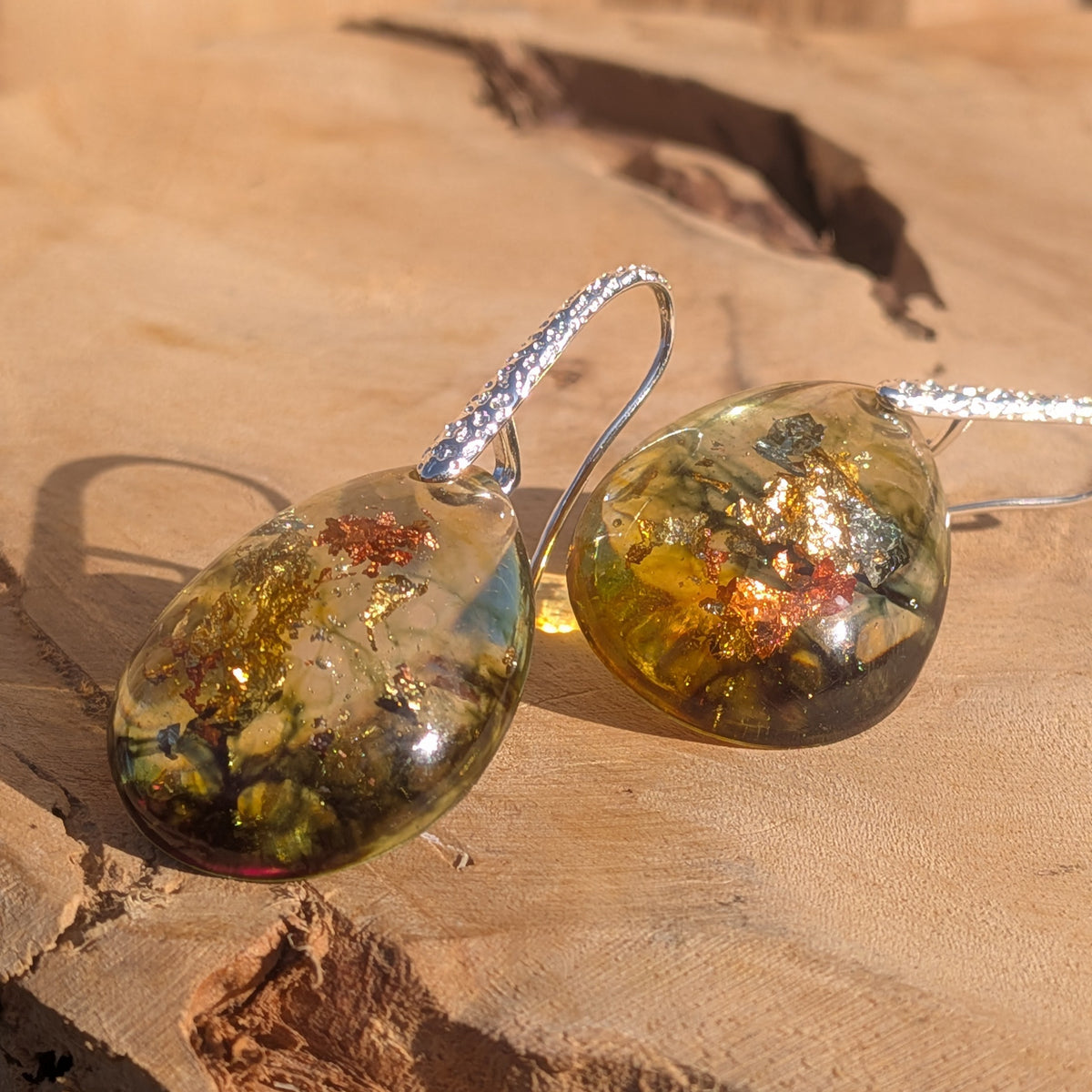 Side-angle view of glossy olive and amber earrings with shimmering metallic flakes, EL-Creations