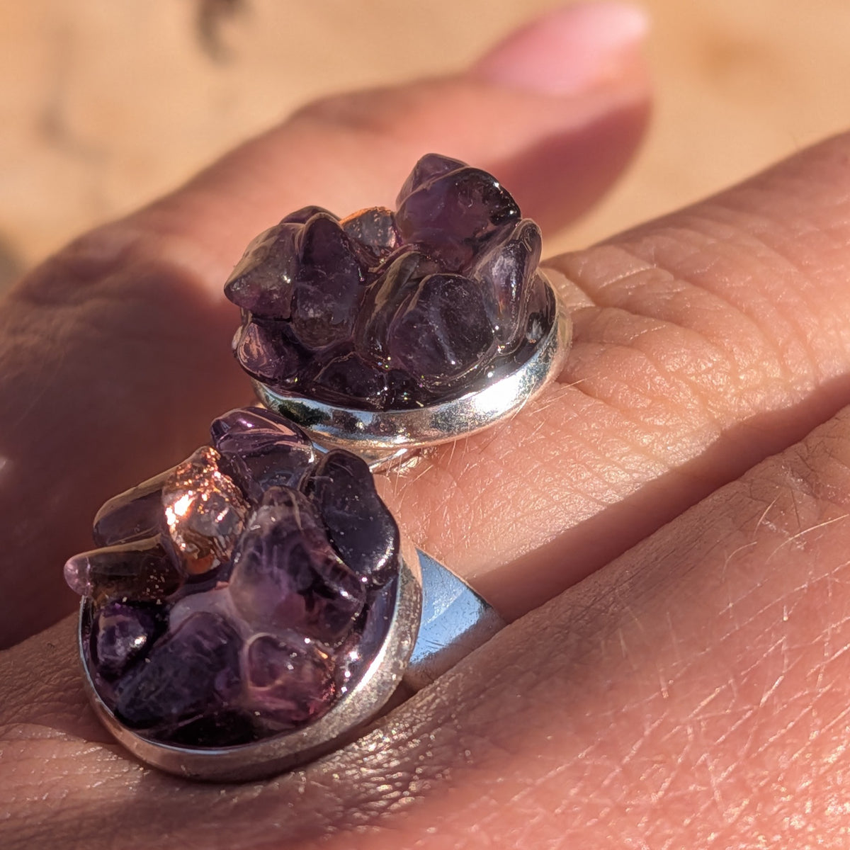 Close-up of the double amethyst ring worn on a finger, showing textured purple stones, EL-Creations