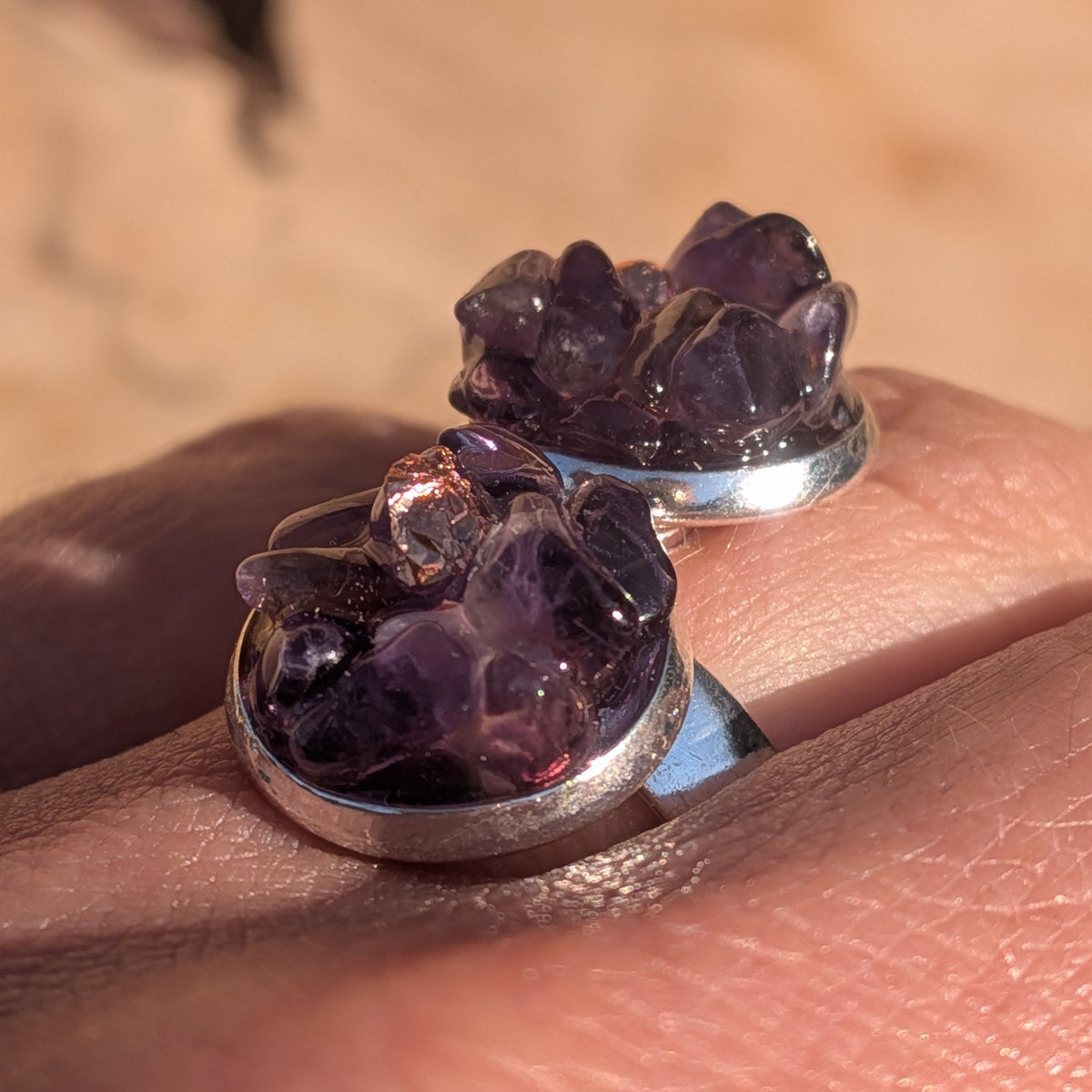 Side view of the amethyst ring worn on a finger with silver-coloured setting rims, EL-Creations