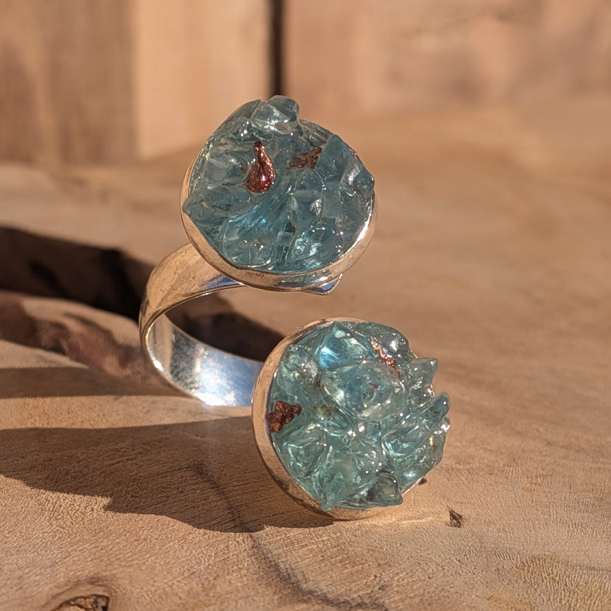 Adjustable blue topaz ring with two 14 mm decorative settings displayed on wood, EL-Creations