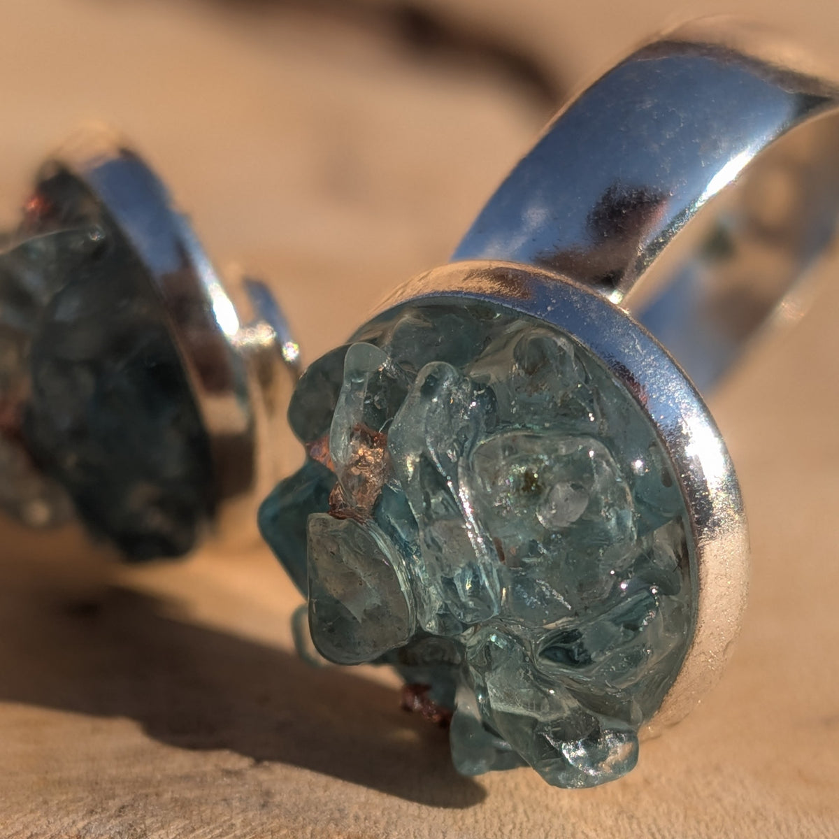 Macro close-up of blue topaz pieces and metallic flakes in a round ring setting, EL-Creations
