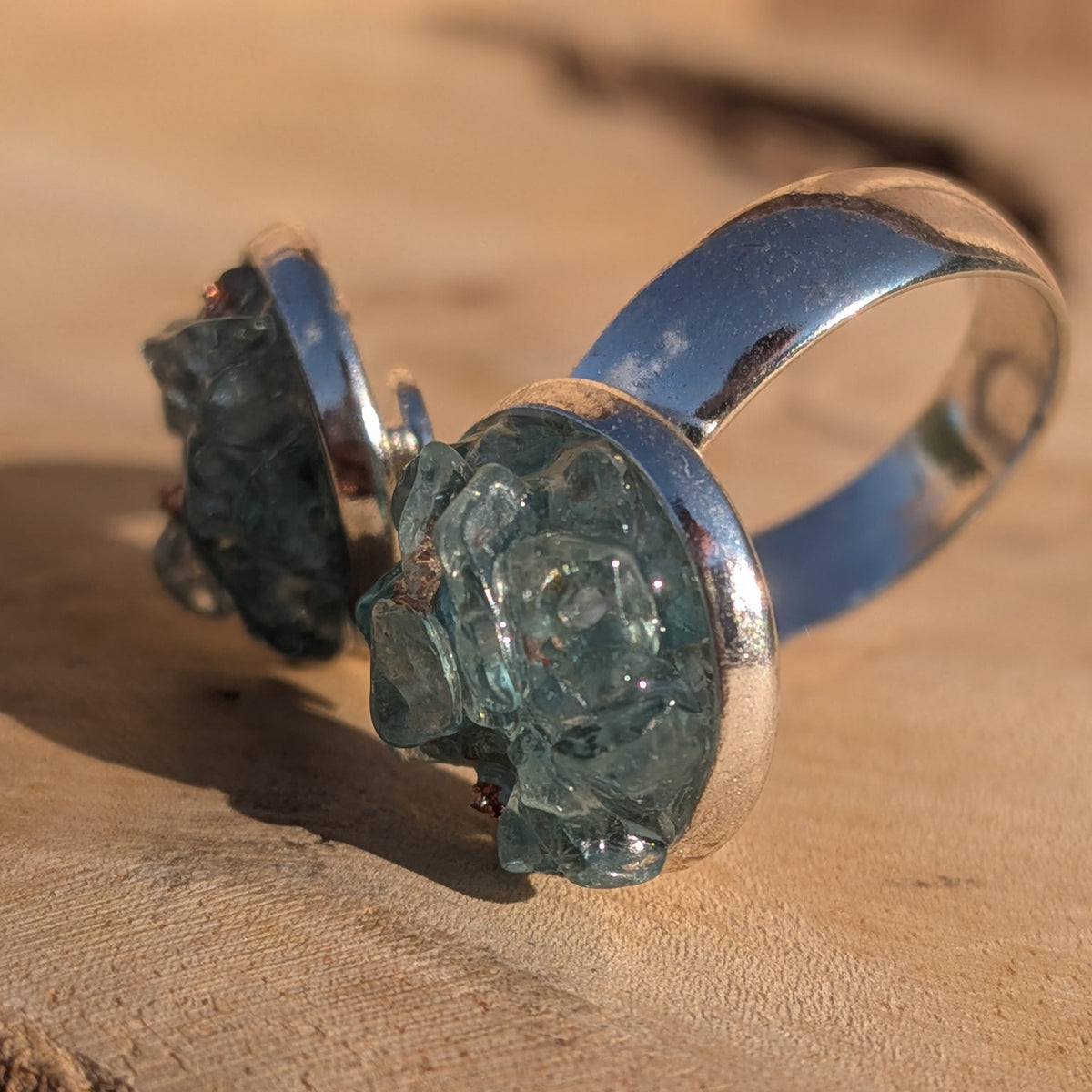 Side view of the blue topaz ring showing its open silver-coloured alloy band, EL-Creations