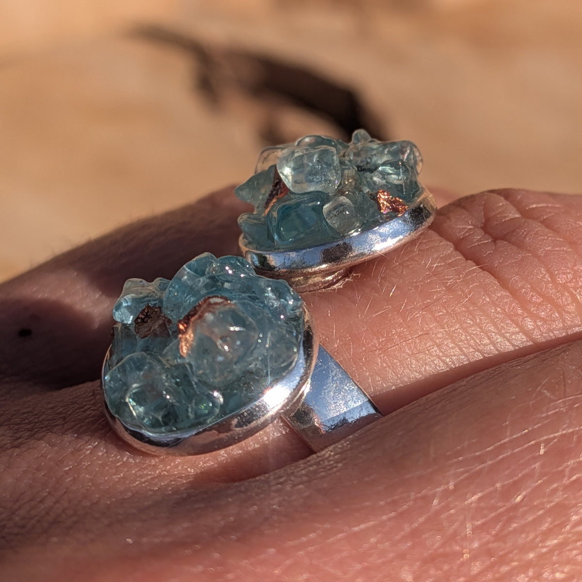 Angled view of the topaz ring worn on a finger showing pale blue gemstone details, EL-Creations