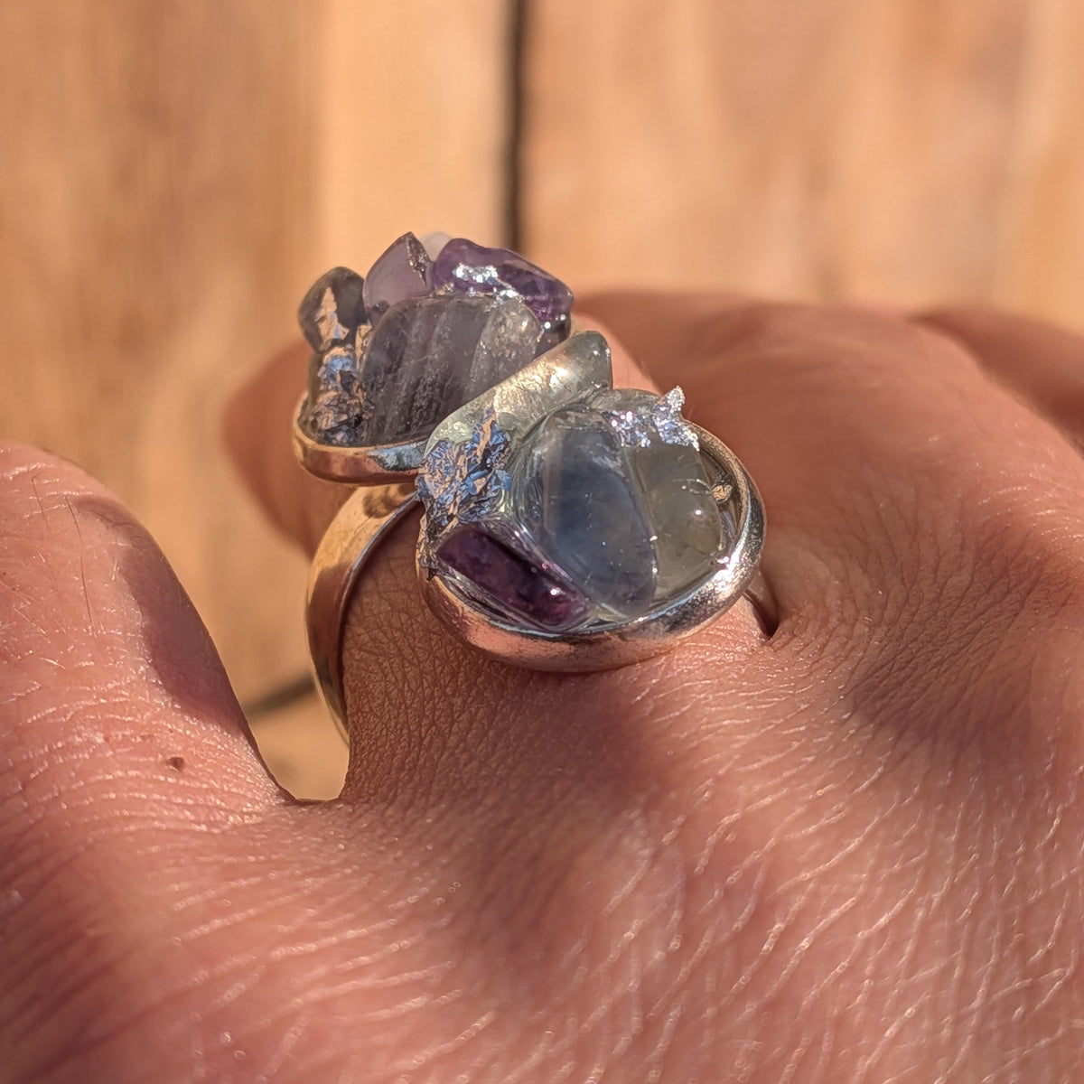 Purple and green fluorite ring worn on a finger with silver flakes between the stones, EL-Creations