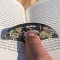 Handmade black resin page holder ring with Queen Anne's Lace – front view on wooden surface – EL-Creations