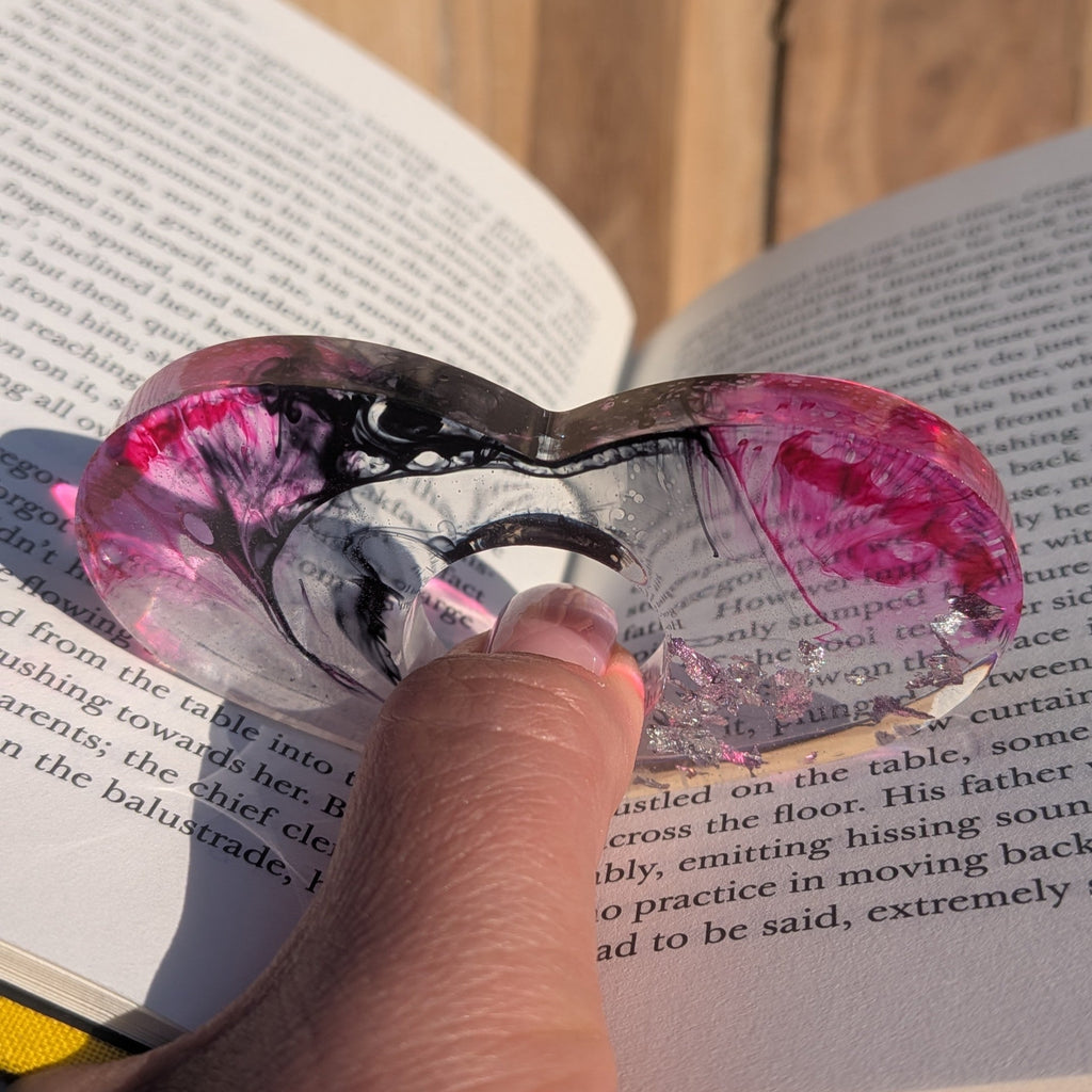 Large handmade resin book ring with silver flakes and crimson black gradient – angled view on sandy surface – EL-Creations