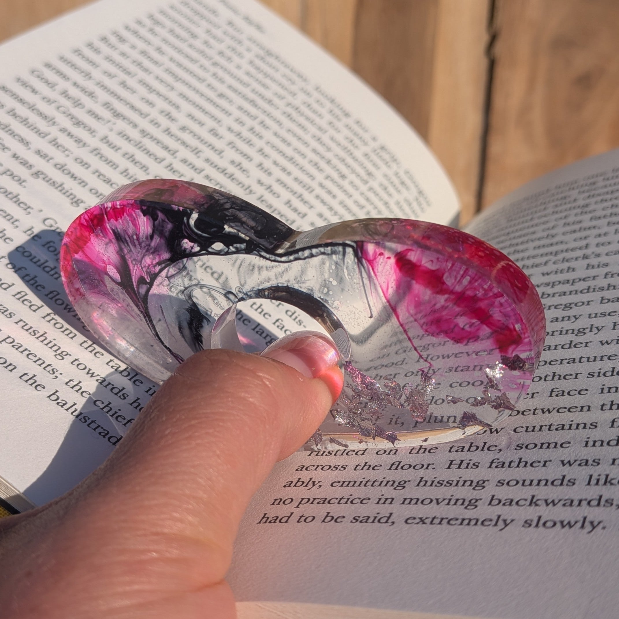 Large resin page holder ring with magenta and black swirl – front view on wooden surface – EL-Creations