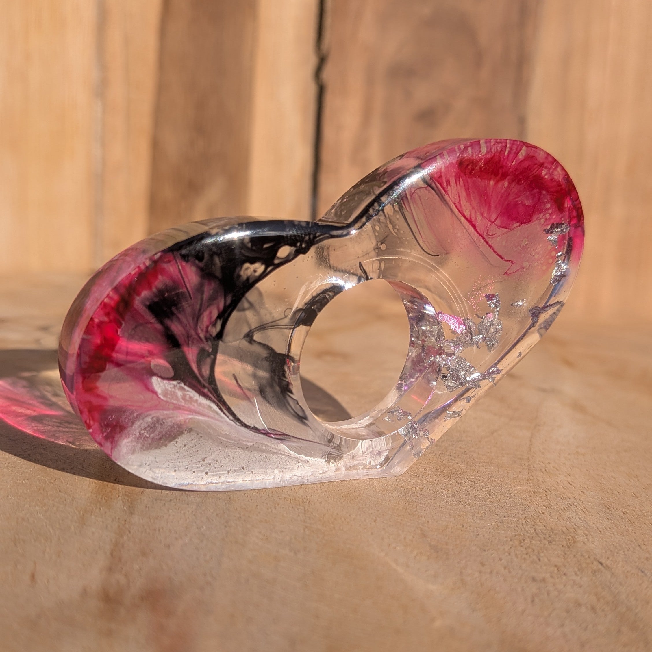 Large resin book ring with magenta crimson and black gradient – full view on sandy surface – EL-Creations