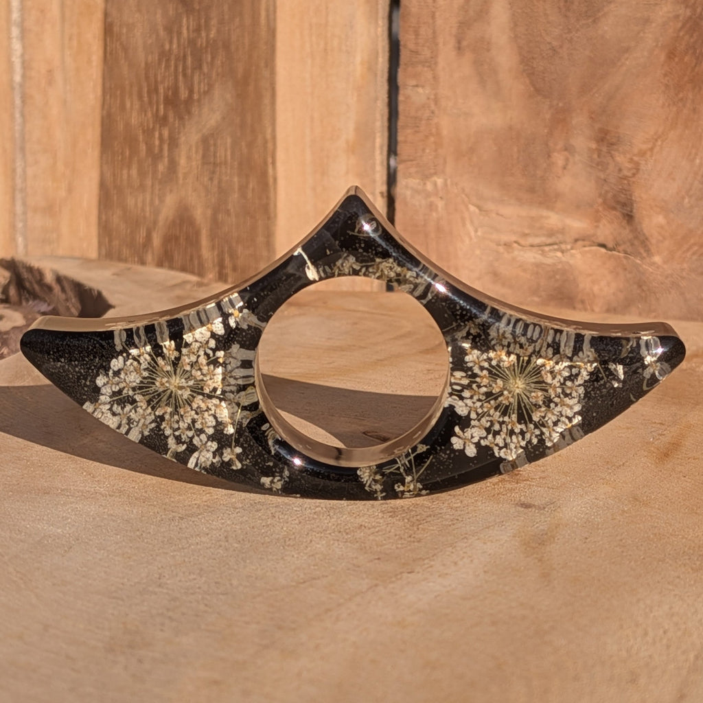 Black resin book ring with real dried flowers – low angle view in warm sunlight – EL-Creations