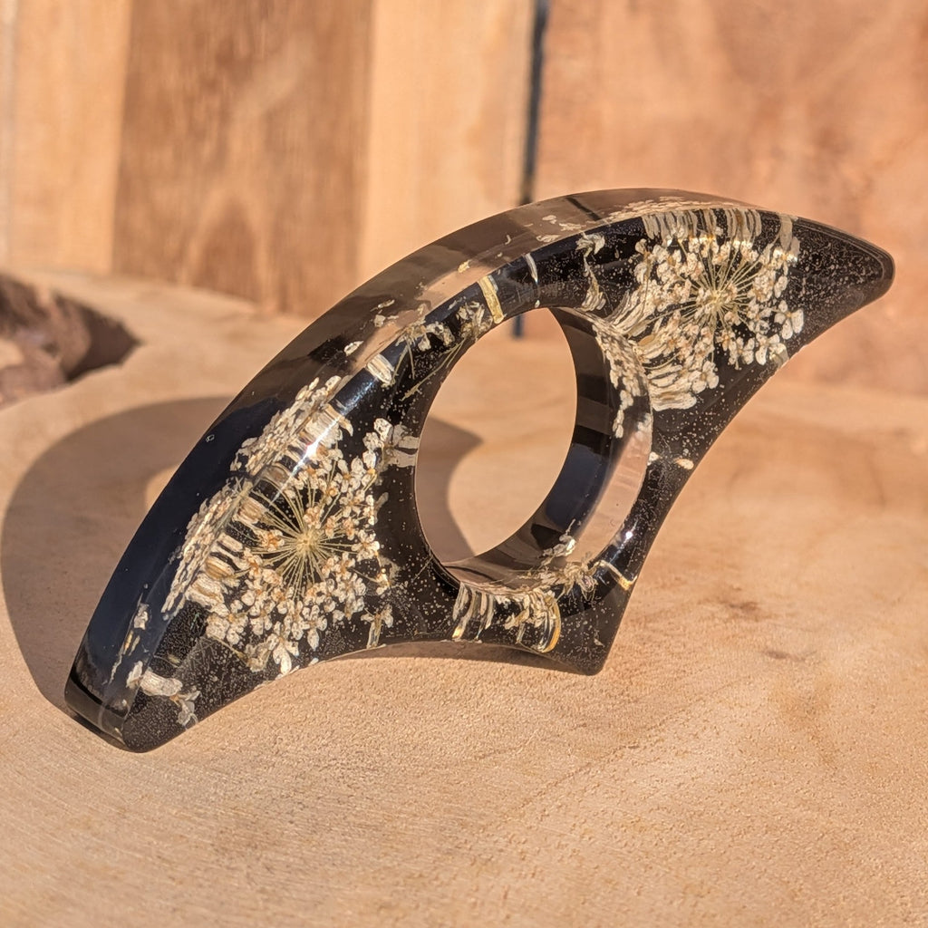 Black resin book ring with dried Queen Anne's Lace flowers – full view on sandy wooden surface – EL-Creations