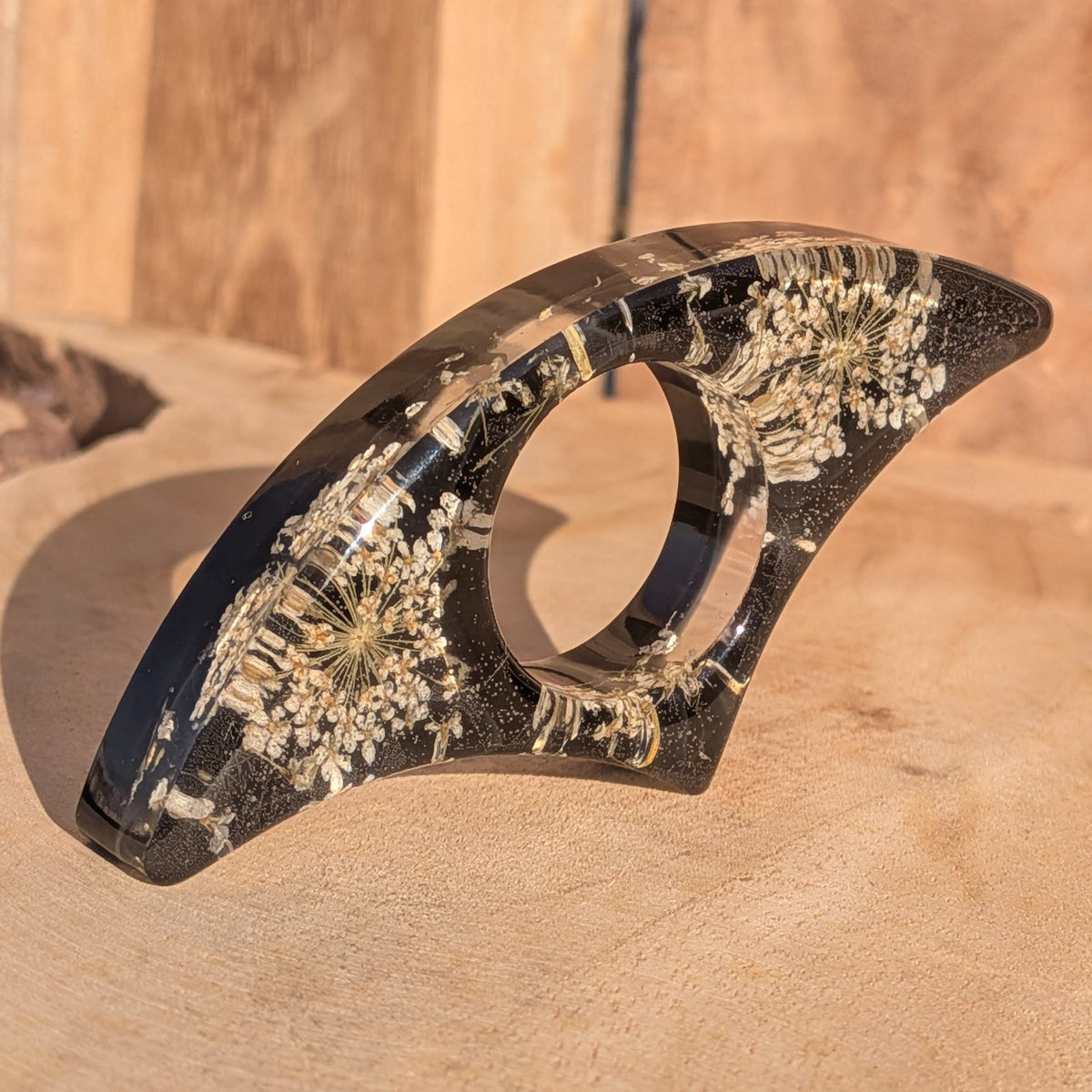 Black resin book ring with dried Queen Anne's Lace flowers – full view on sandy wooden surface – EL-Creations