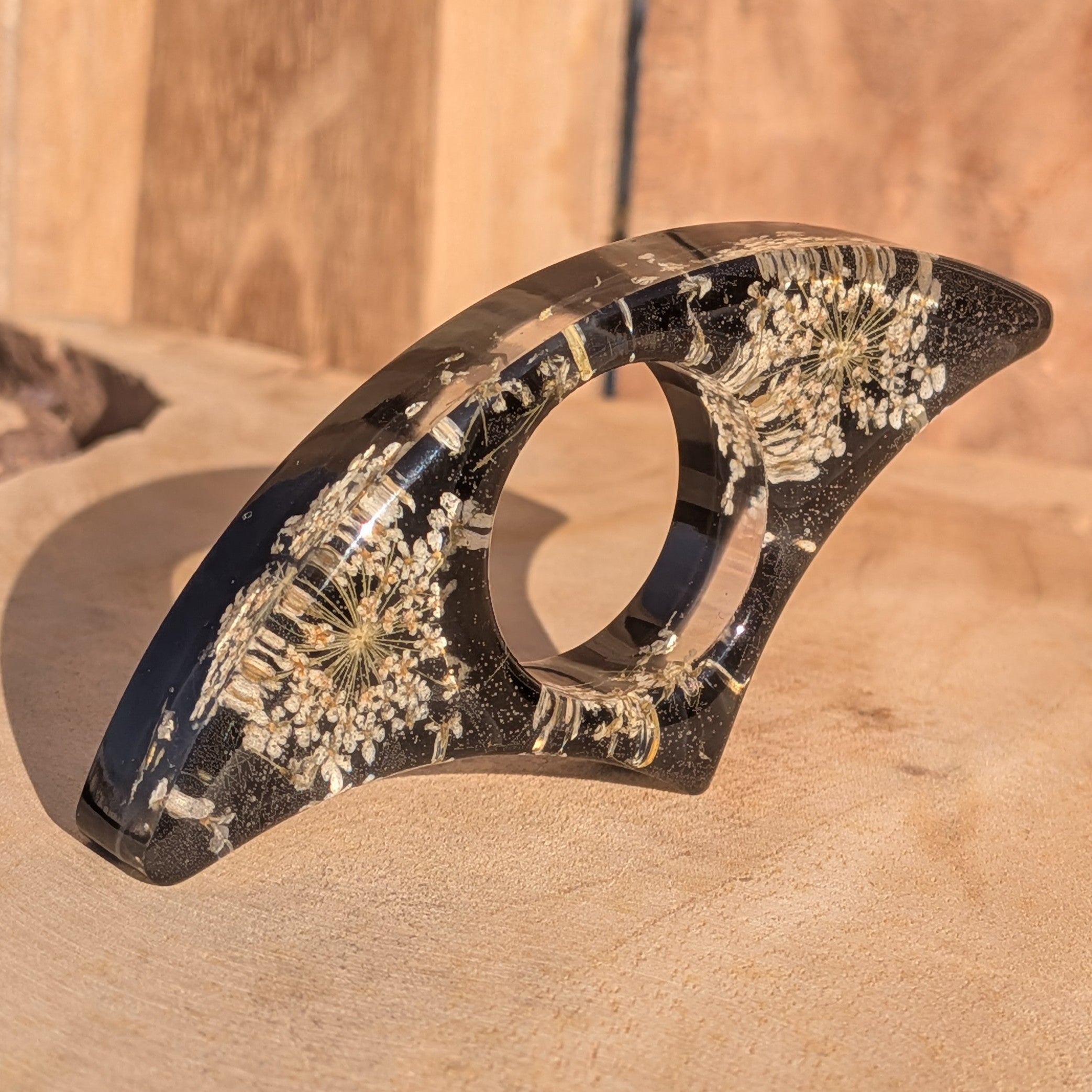 Black resin book ring with dried Queen Anne's Lace flowers – full view on sandy wooden surface – EL-Creations