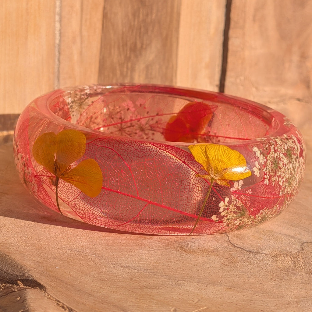 Botanical resin bangle with skeleton leaf and yellow wildflower petals – flat lay top view on wooden surface – EL-Creations