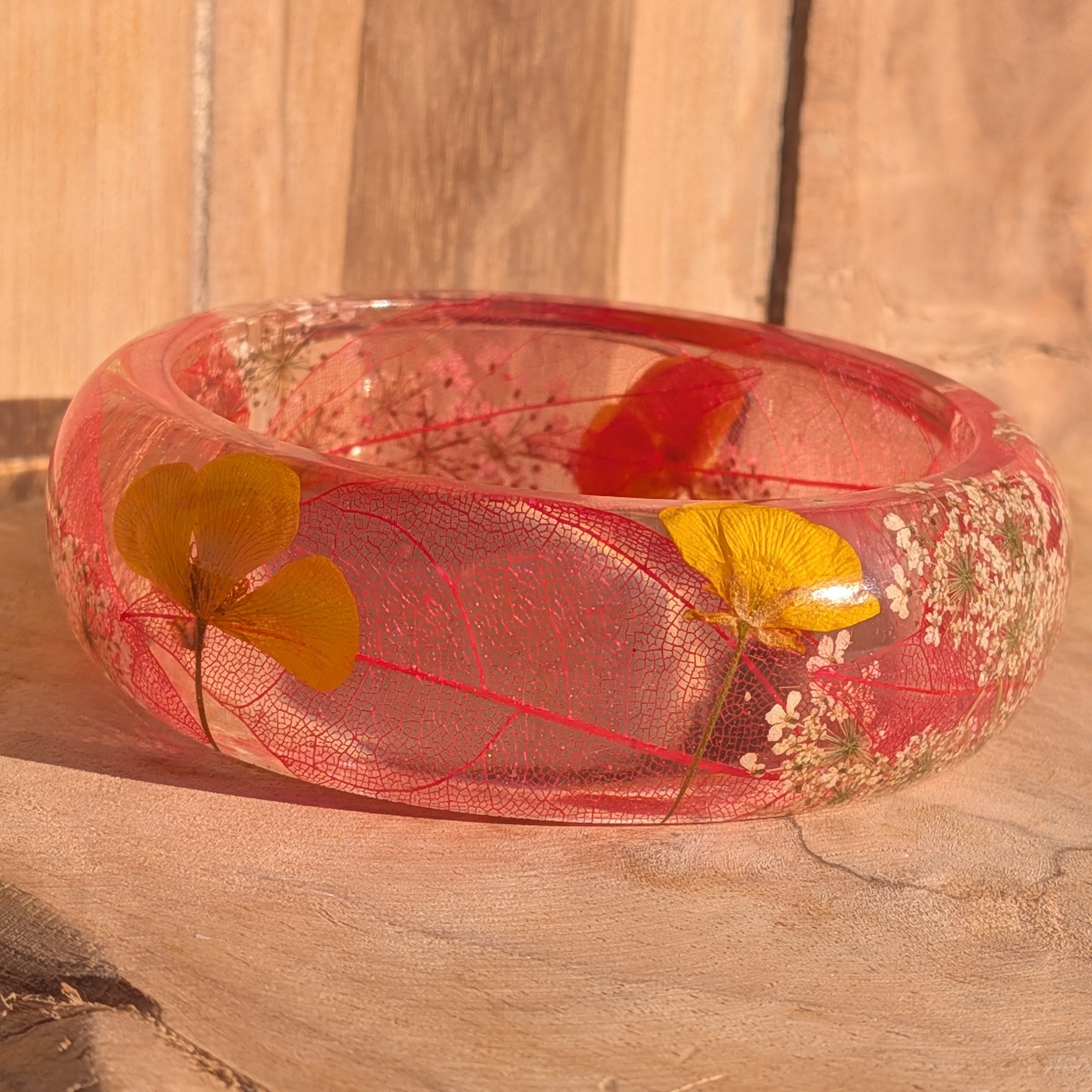 Botanical resin bangle with skeleton leaf and yellow wildflower petals – flat lay top view on wooden surface – EL-Creations