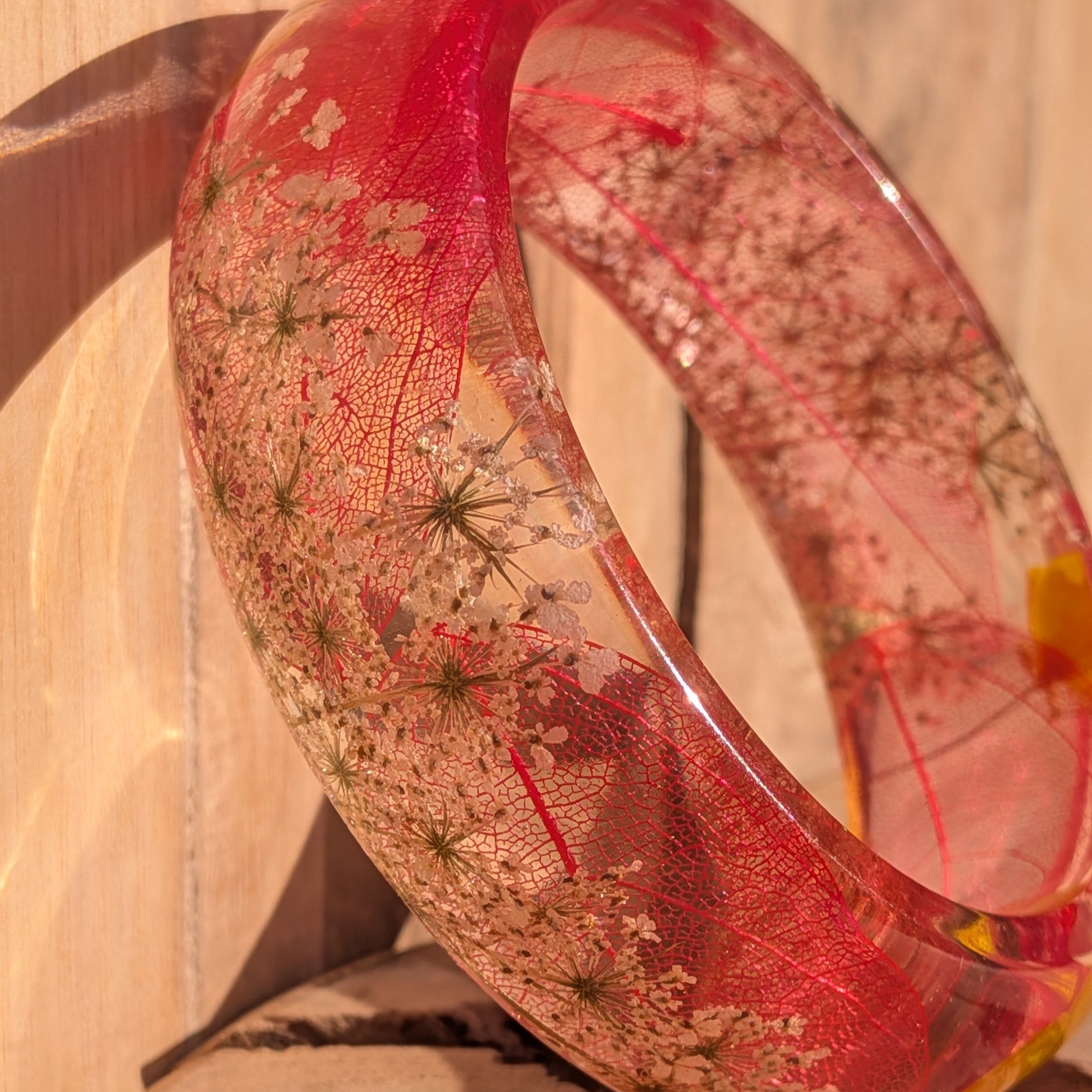 Handmade resin bangle with red skeleton leaf – worn on wrist showing fit and scale – EL-Creations