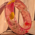 Clear resin bangle with Queen Anne's Lace and yellow wildflowers – lifestyle wrist shot in warm sunlight – EL-Creations