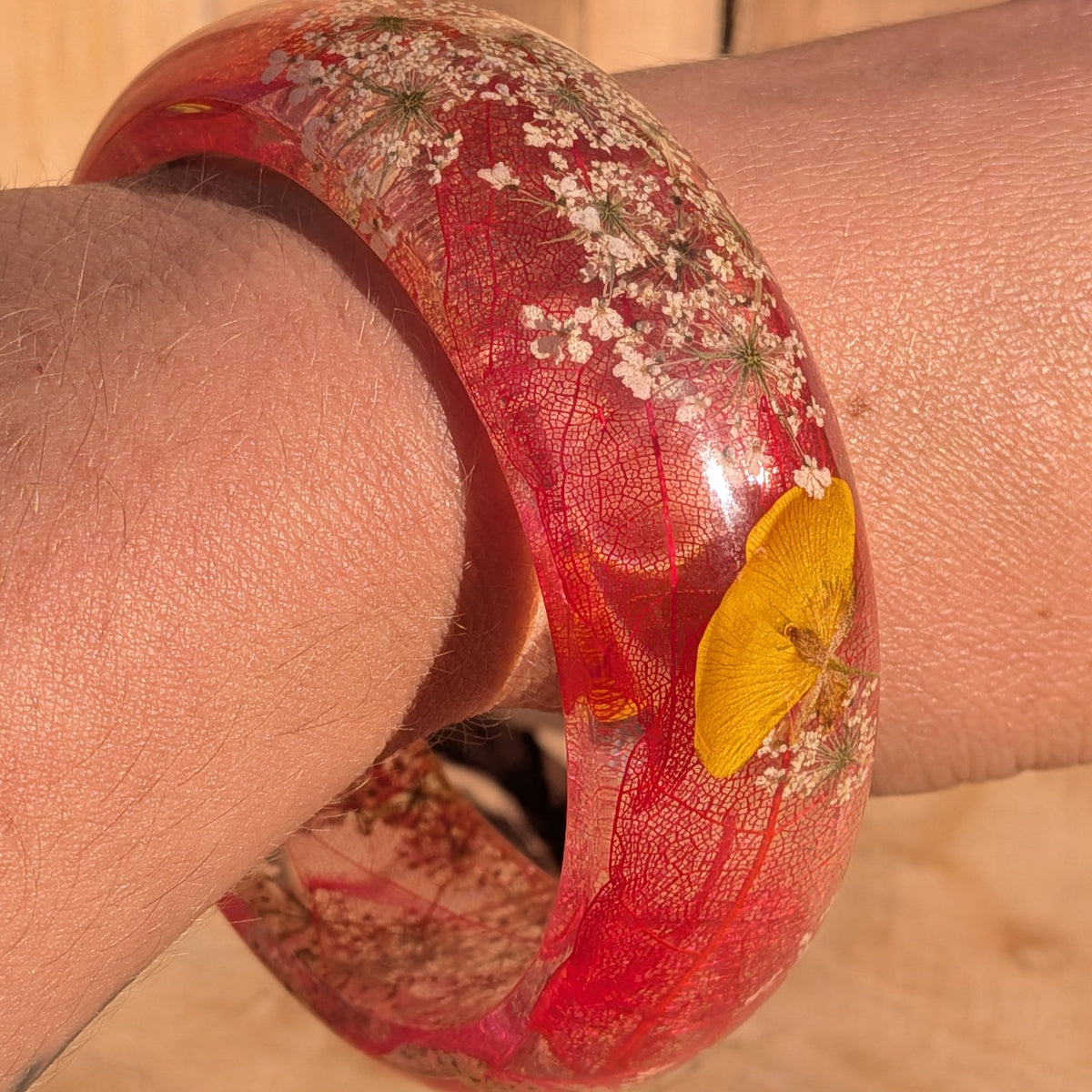 Clear resin bangle with skeleton leaf and wildflowers – wrist lifestyle shot in natural light – EL-Creations