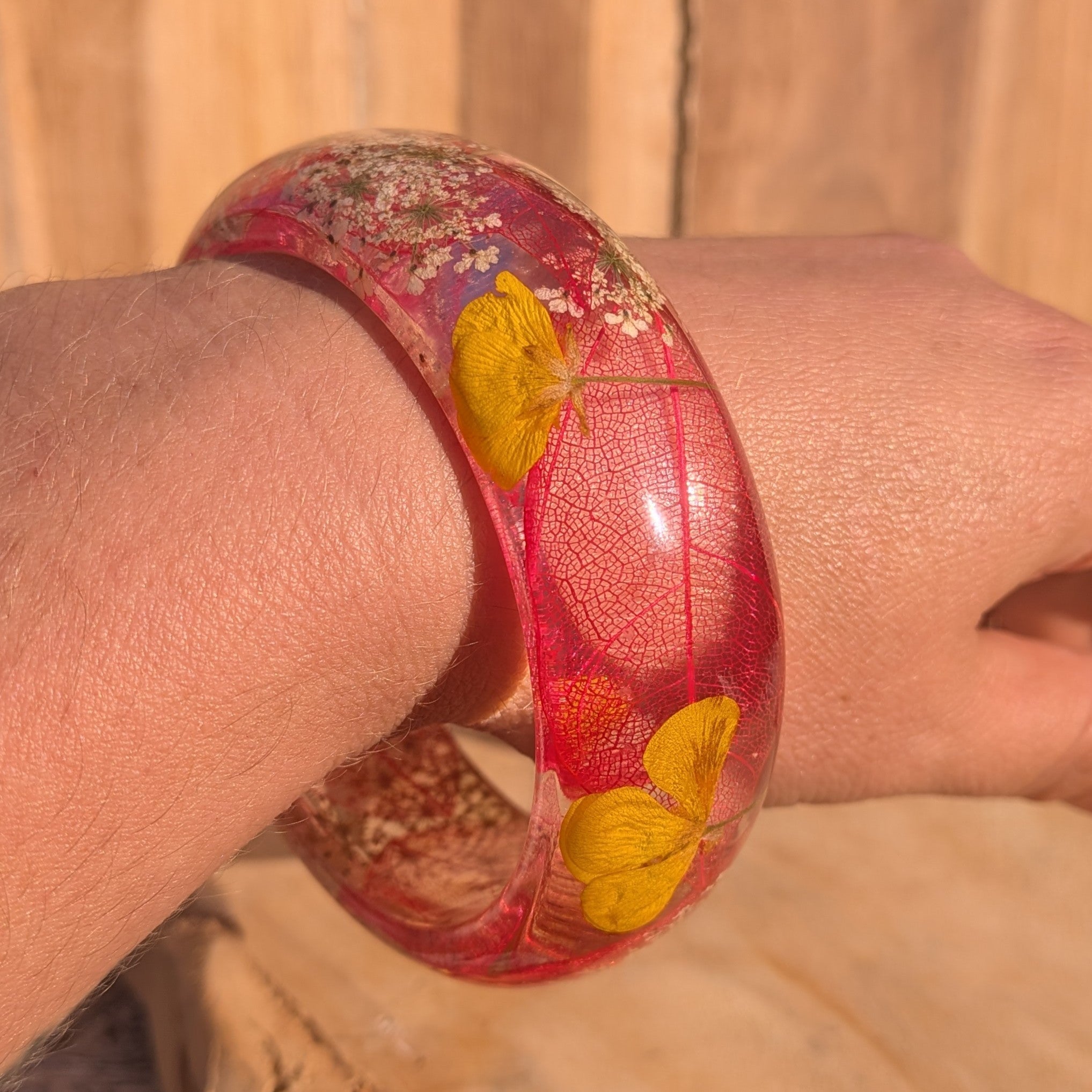 Botanical resin bangle with red skeleton leaf and yellow wildflower petals – full wrist view – EL-Creations