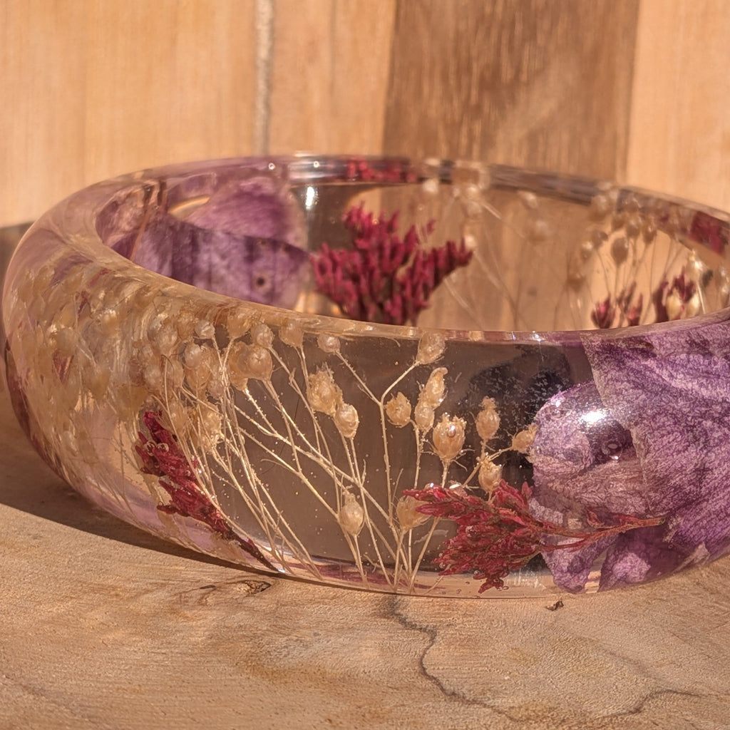 Resin bangle with dried orchid and wild flowers – full ring view on wooden surface in warm light – EL-Creations