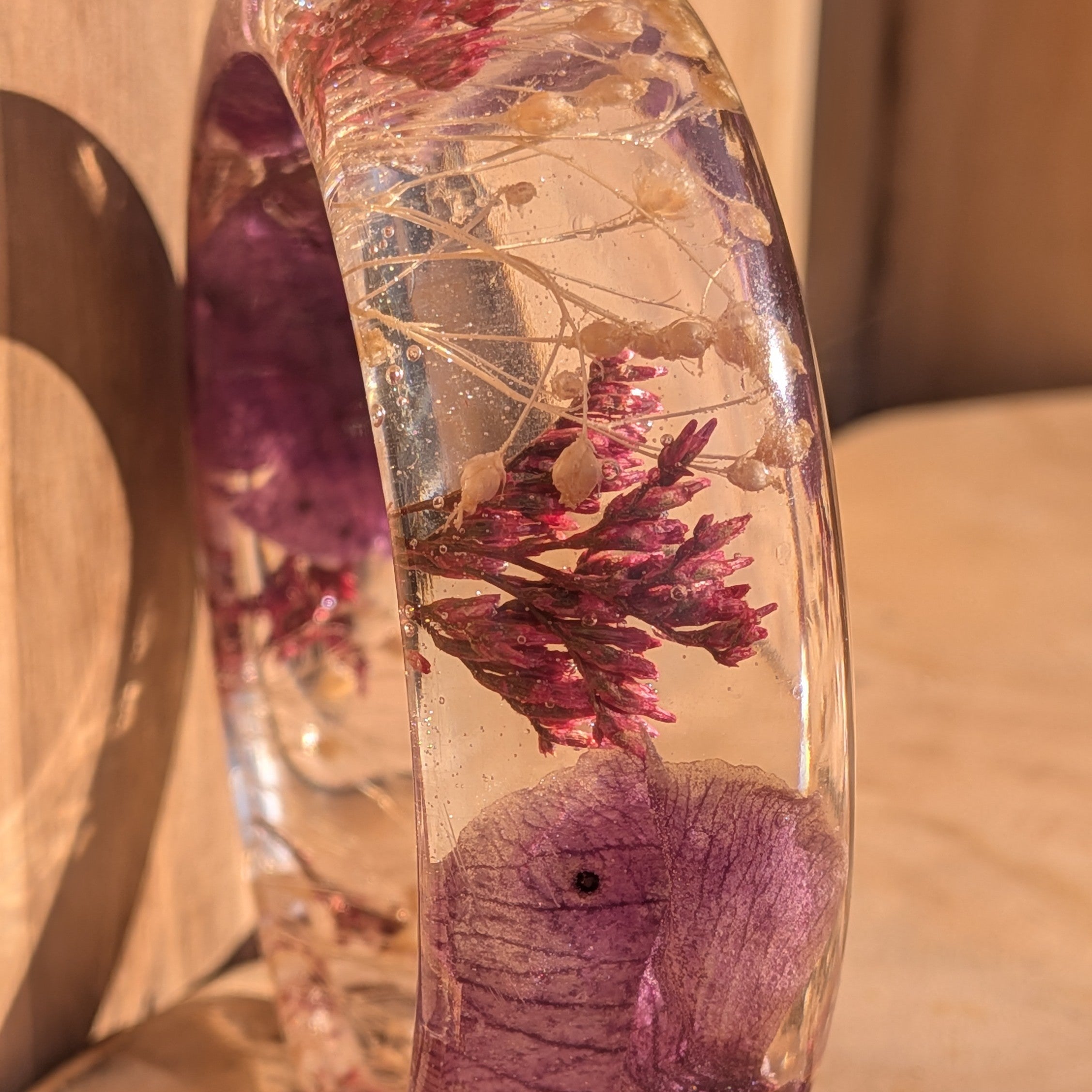 Clear resin bangle with orchid and heather – lifestyle wrist shot in warm sunlight – EL-Creations