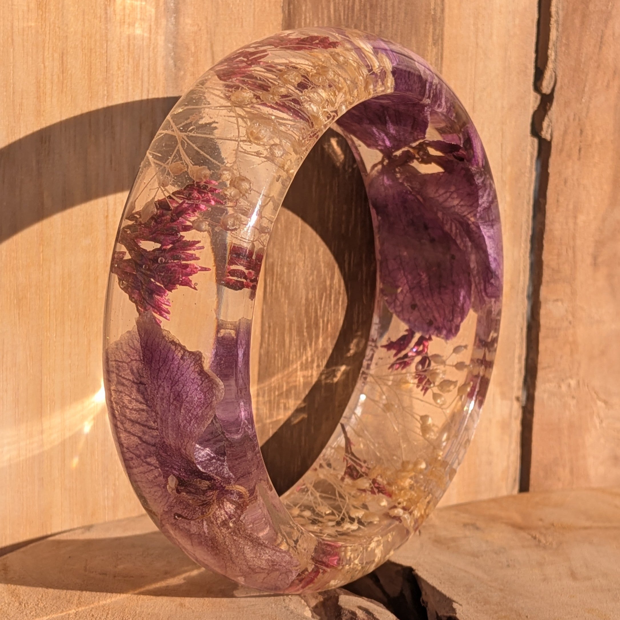 Resin botanical bangle with orchid and heather – wrist lifestyle shot showing glossy domed profile – EL-Creations