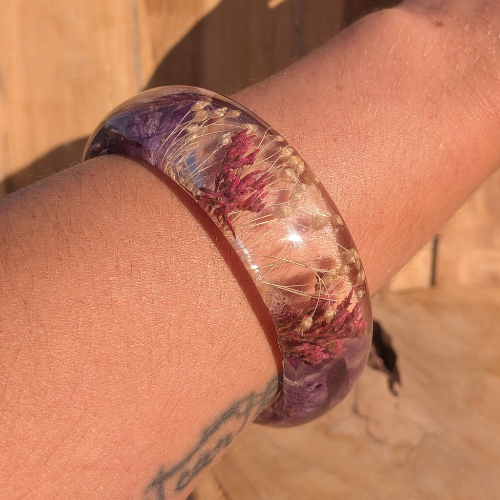Handmade resin orchid bangle – wrist lifestyle shot with warm wooden background – EL-Creations