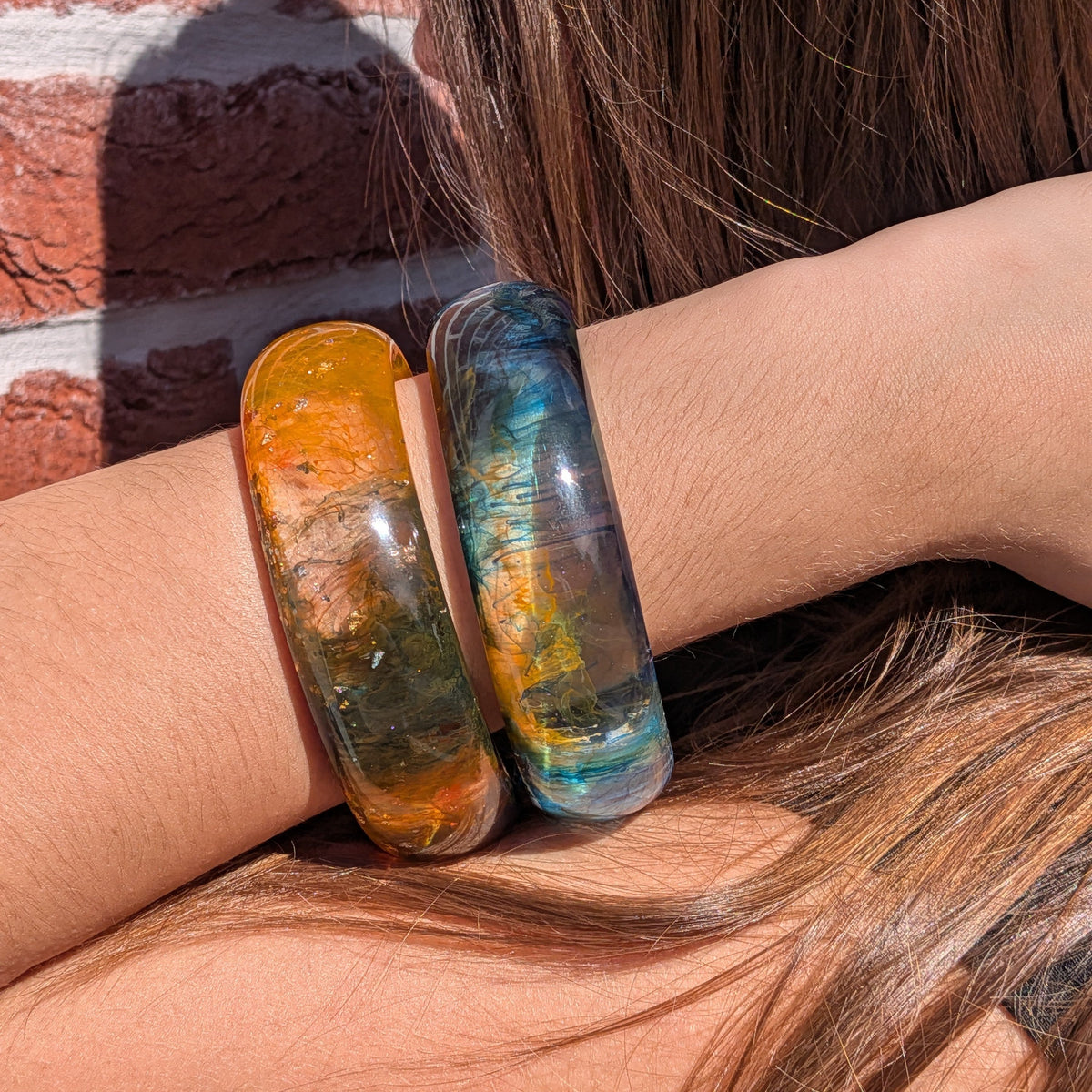 Deep ocean resin bangle worn on wrist paired with orange resin bangle outdoors – EL-Creations