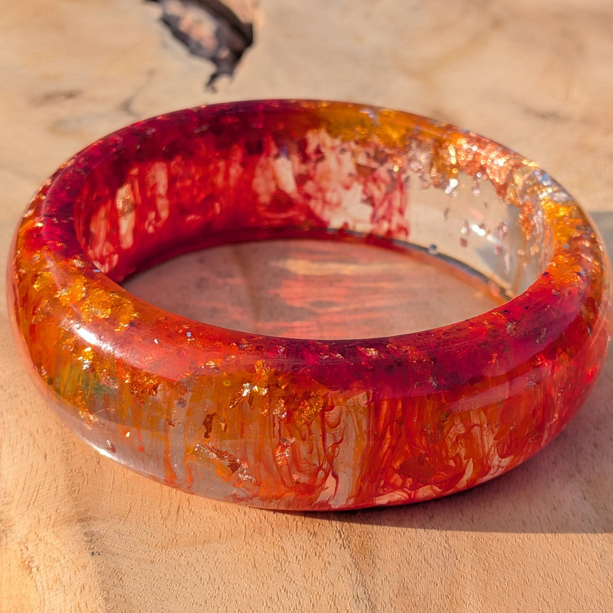 Angled view of handmade red orange resin bangle showing inner diameter and mirror finish – EL-Creations
