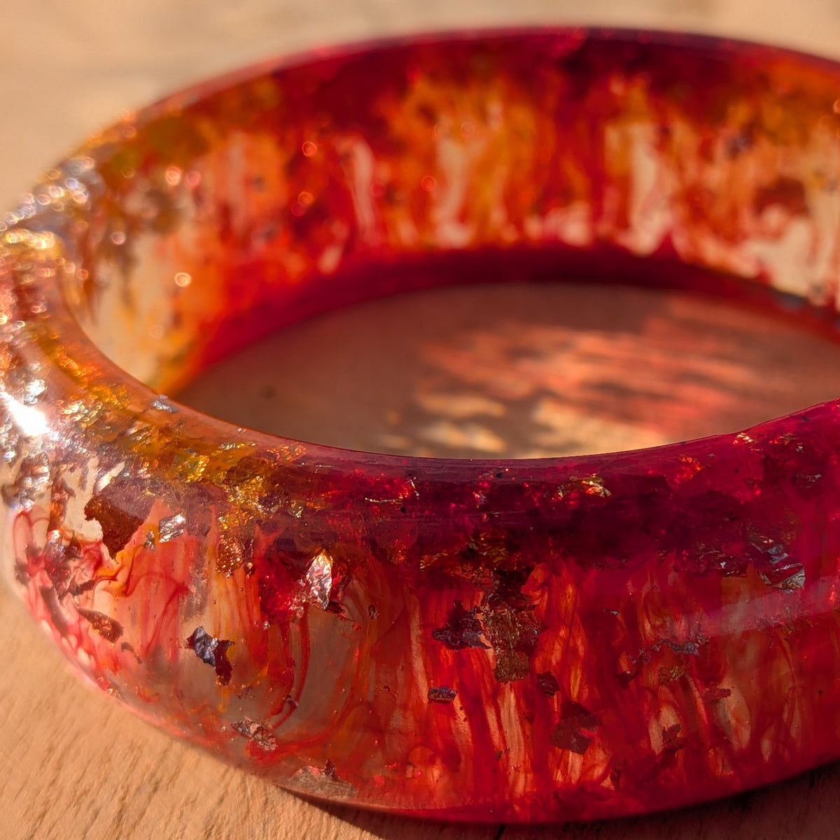 Macro close-up of gold and orange alcohol ink swirl in red epoxy resin bangle – EL-Creations
