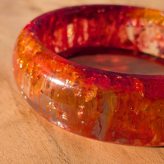 Phoenix fire resin bangle worn on wrist against brick wall background – EL-Creations