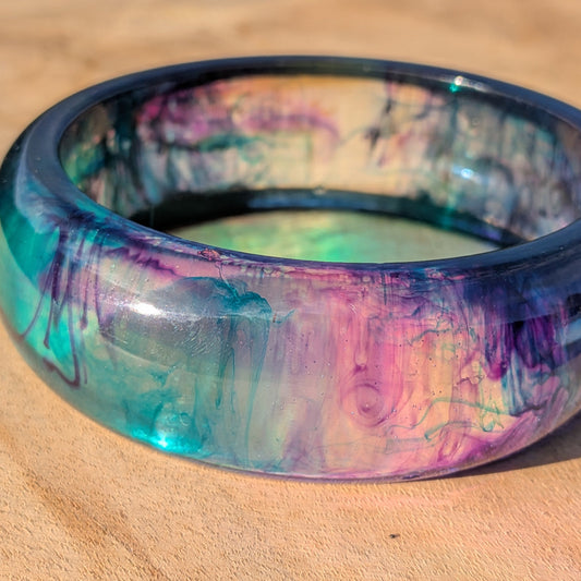 Purple midnight resin bangle bracelet on wrist against brick wall – EL-Creations