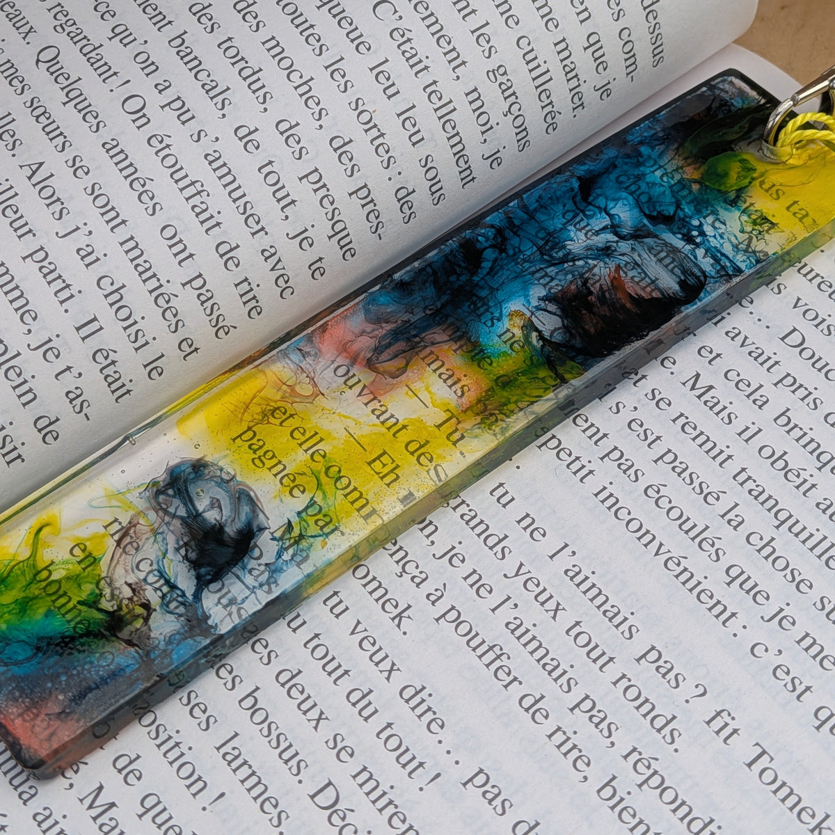 Handmade resin bookmark with teal yellow black alcohol ink swirl on open book – EL-Creations
