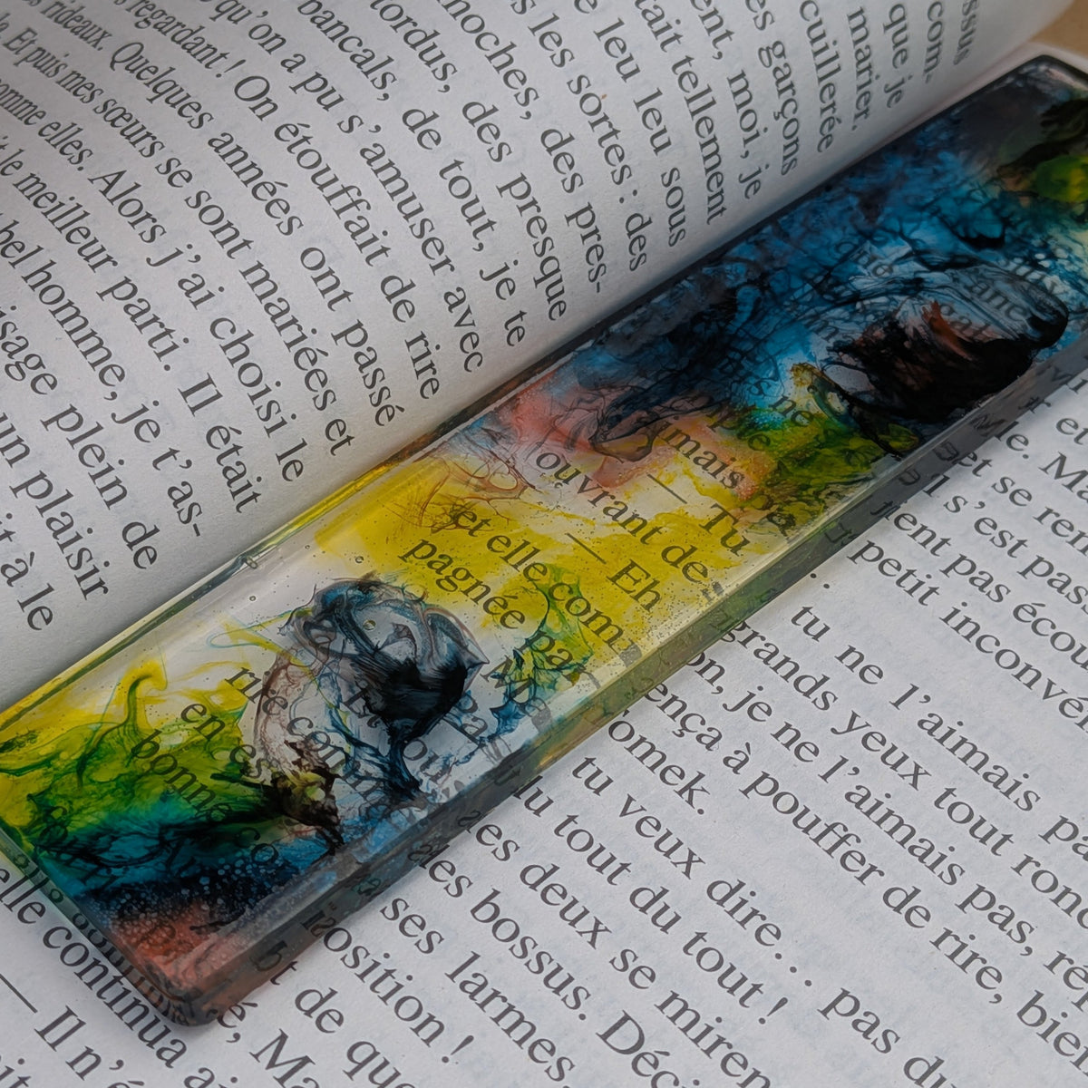 Resin bookmark keychain lying diagonally across open book pages – EL-Creations