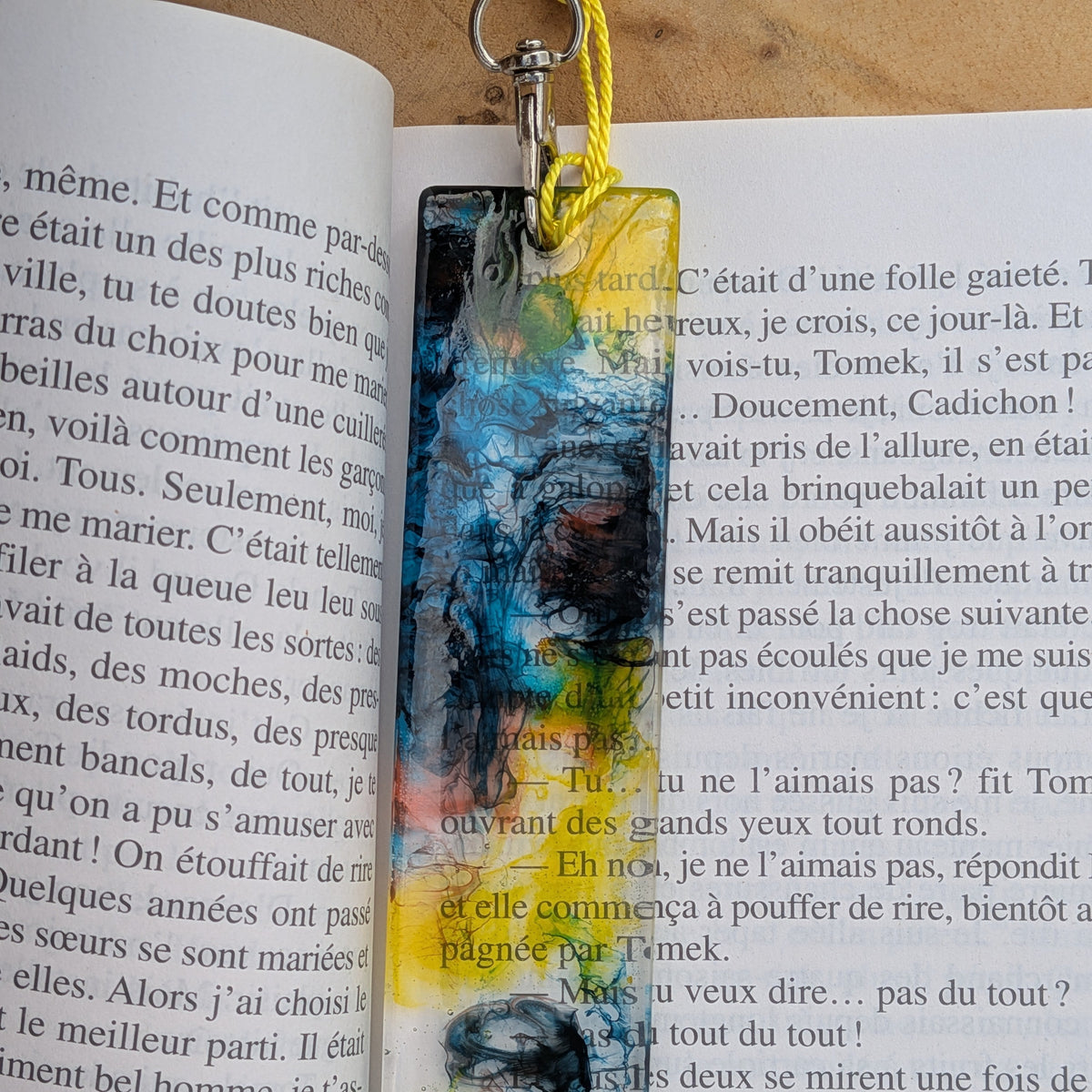 Resin bookmark with abstract teal black yellow pattern held above book – EL-Creations